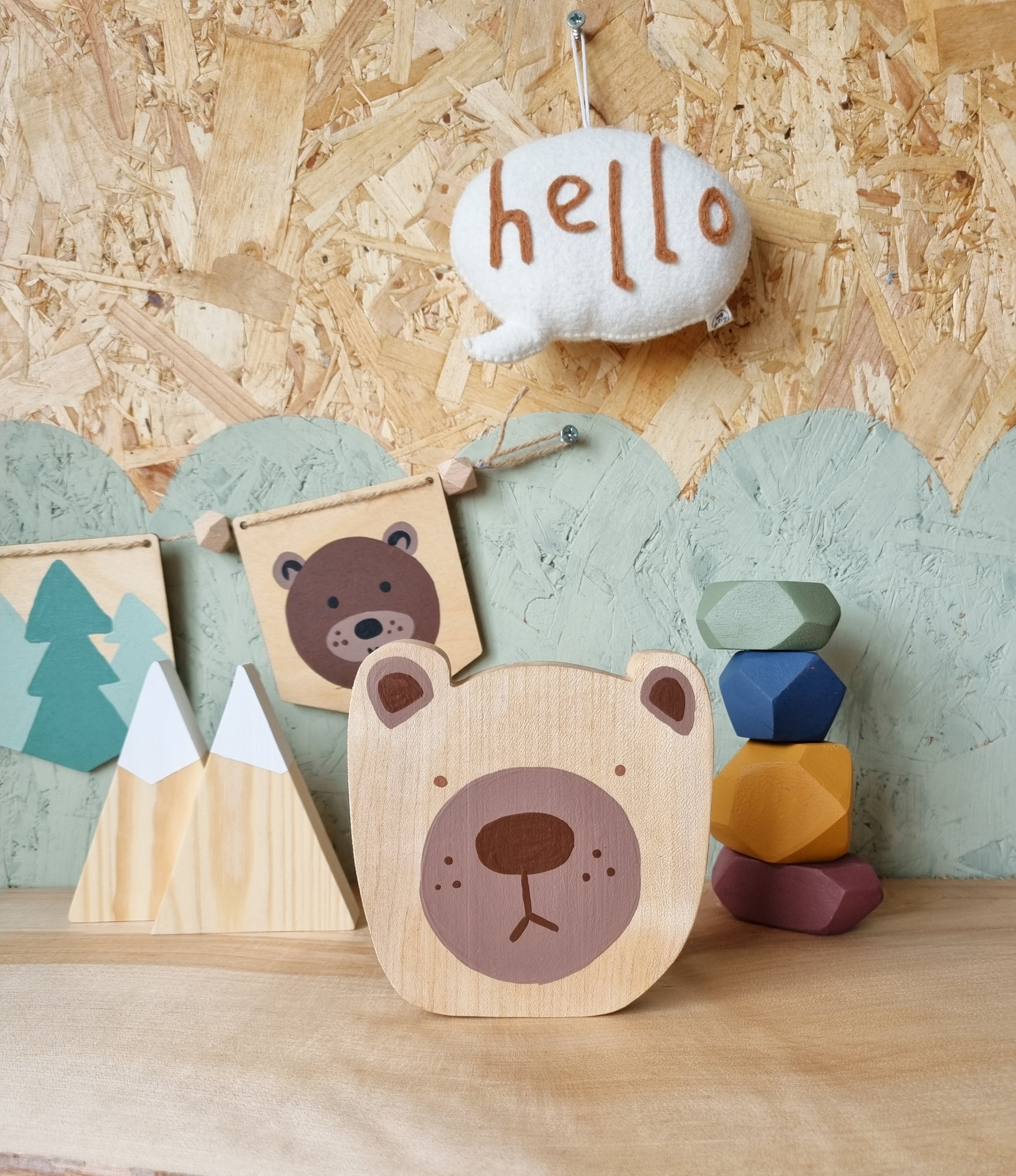 Hand painted wooden bear head on display next to a handpainted wooden bear and forest bunting decoration.