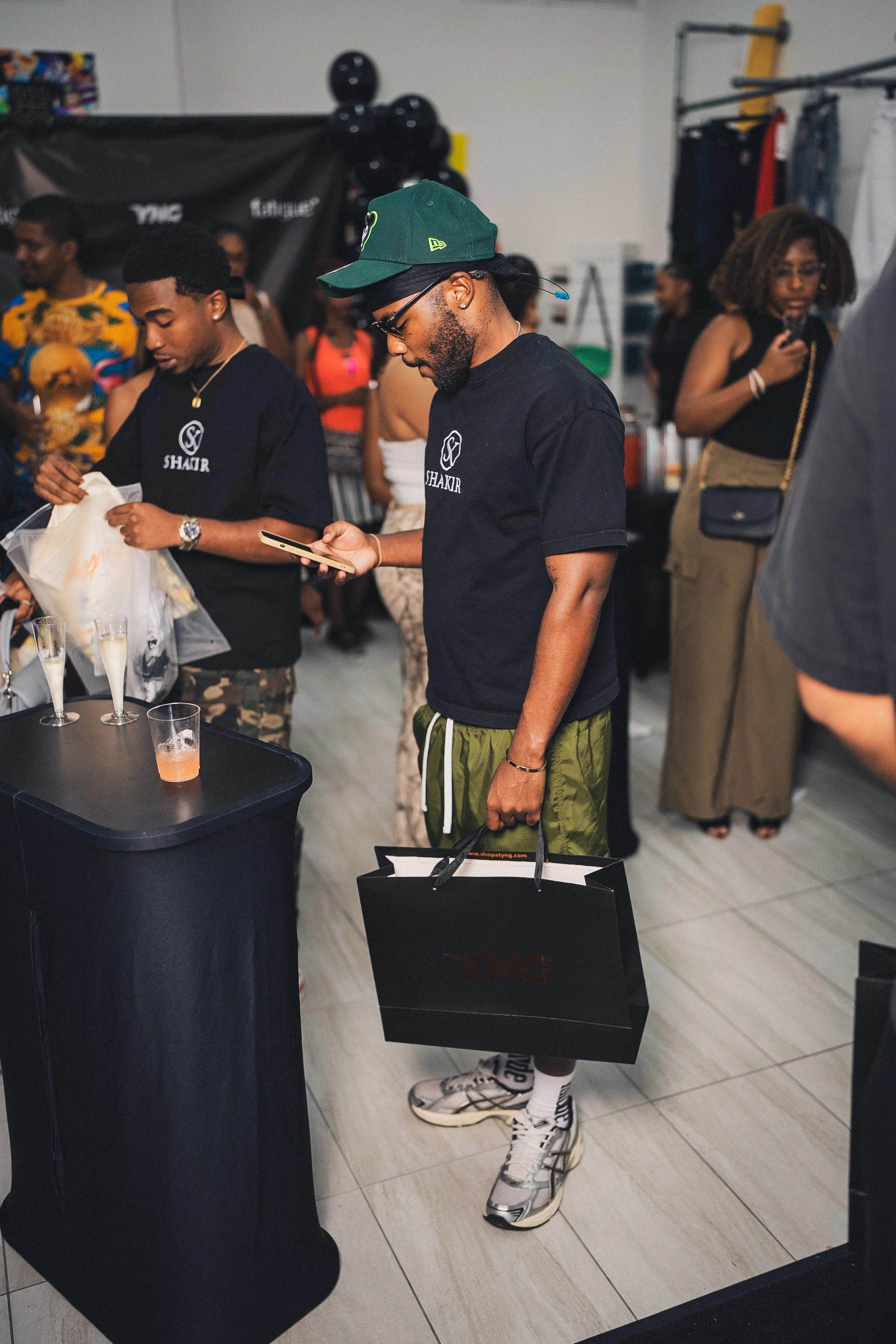 A man holding a shopping bag and looking at his phone during a social gathering or party.