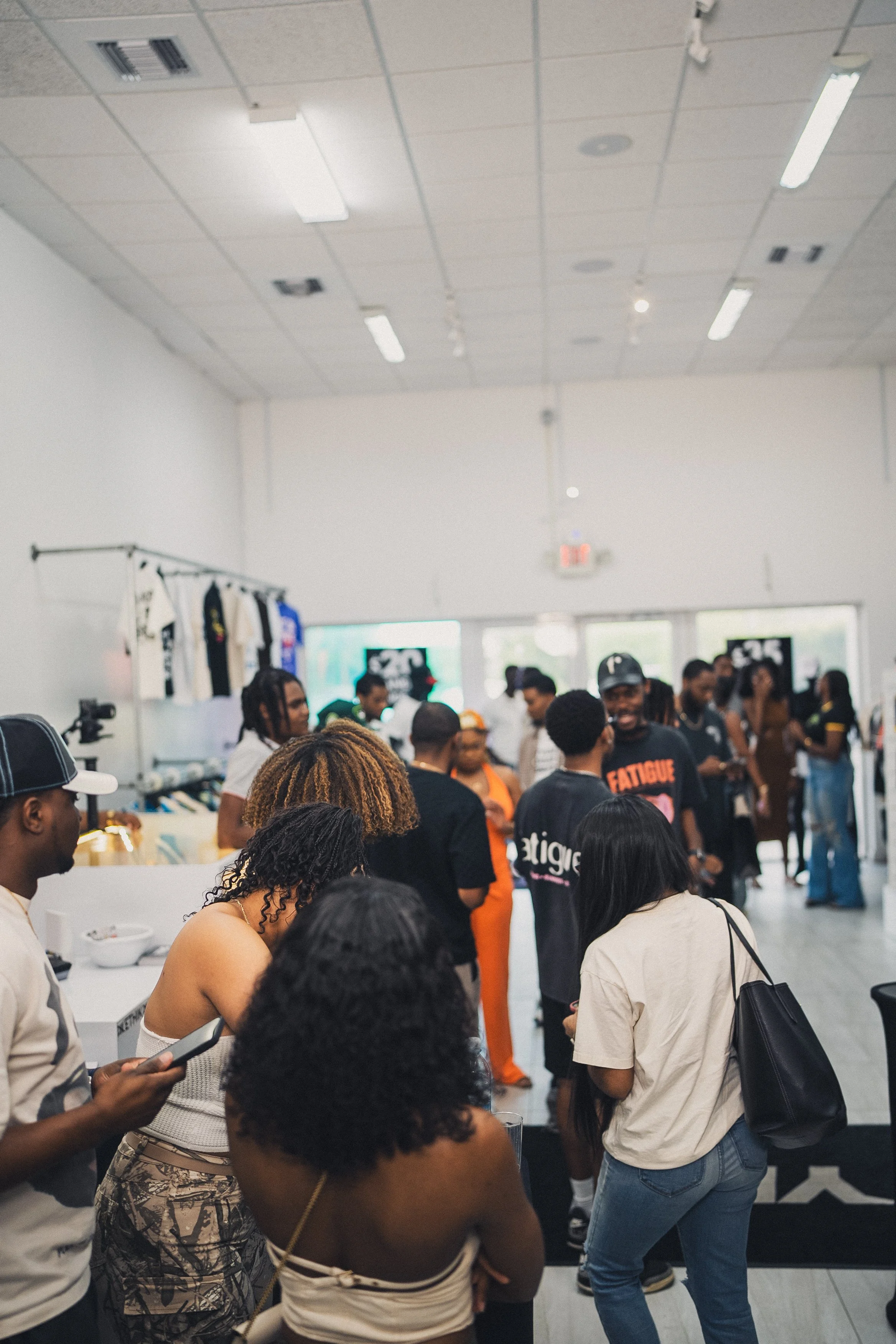 People shopping and socializing inside a retail store with clothing displays