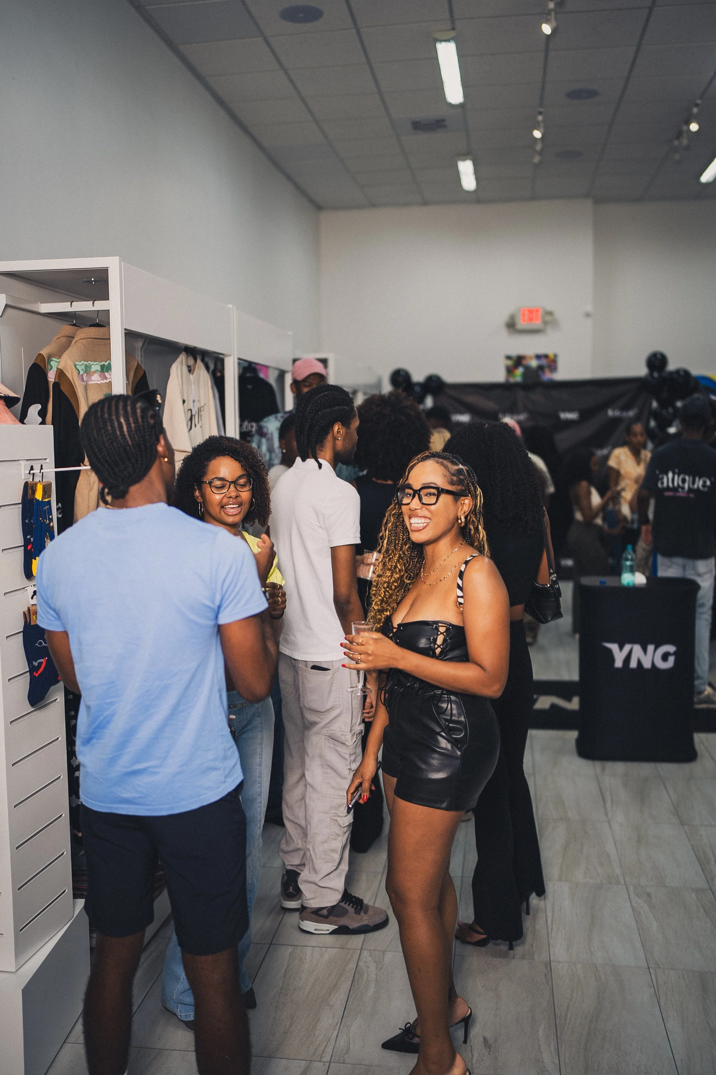 Group of people socializing at an indoor event with merchandise displays.