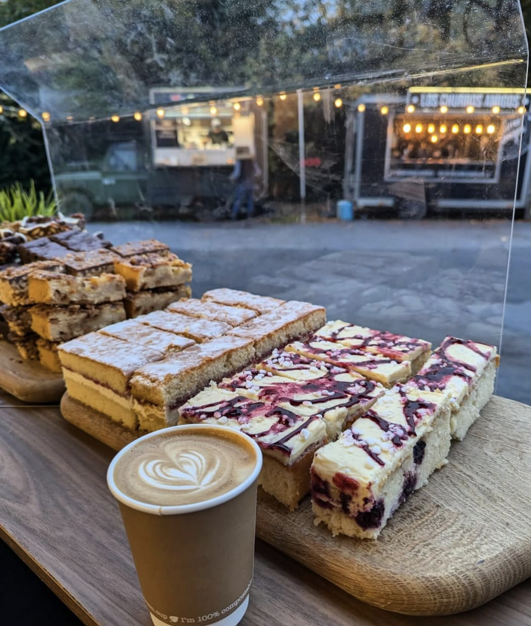 a flat white an variety of cakes on the counter of a mobile coffee bar at an outdoor event