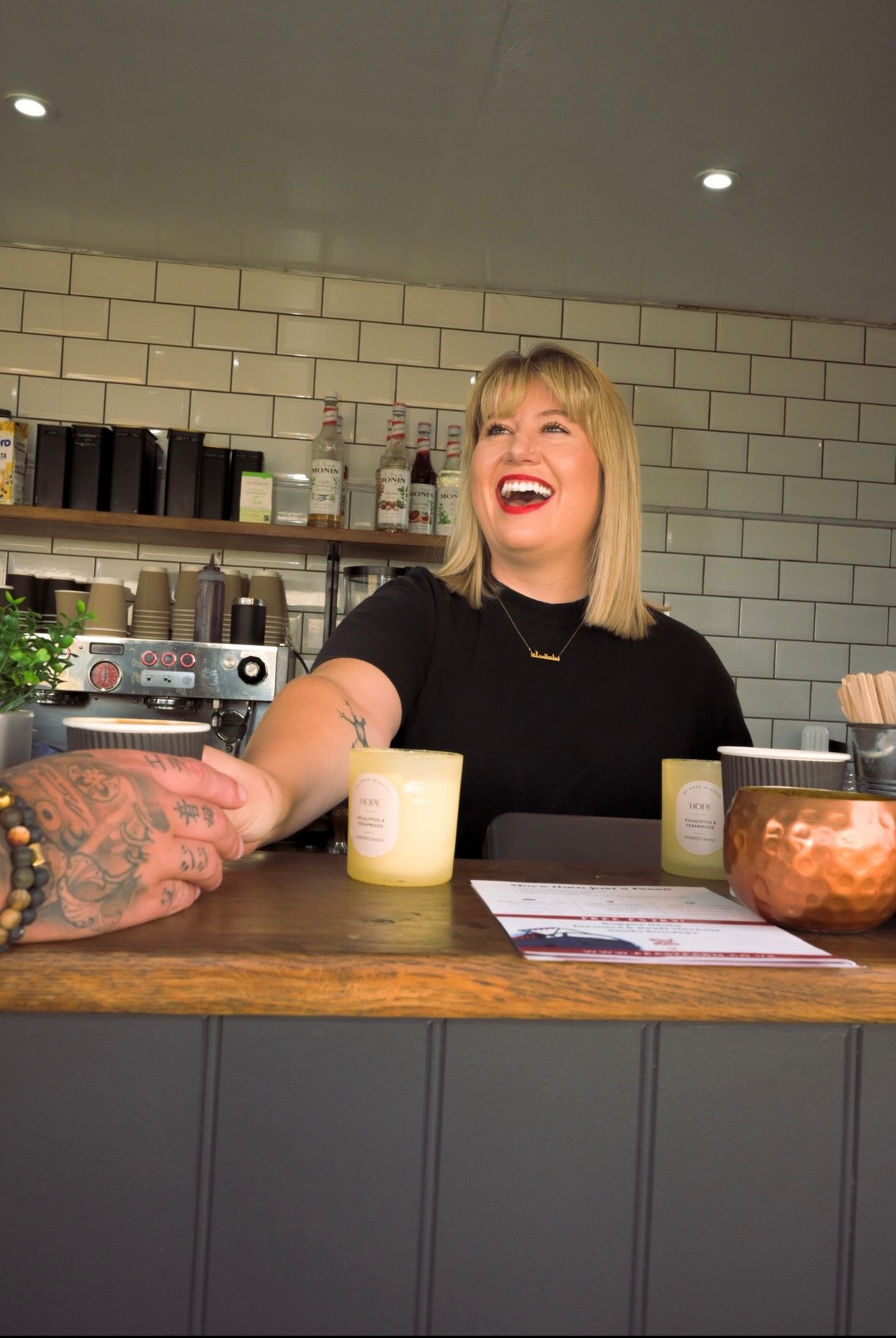 a smiling barista serving good coffee inside a mobile container cafe