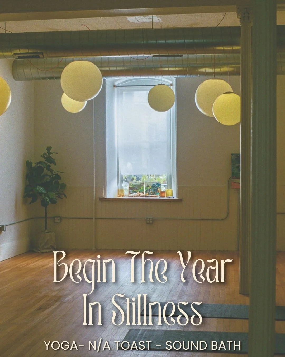 A serene and empty yoga studio with wooden floors, hanging round lamps, a large window with a sheer curtain, a potted plant in the corner, a small television on a stand, and candles on the windowsill. Text overlay reads: "Begin The Year In Stillness. Yoga - N/A Toast - Sound Bath."