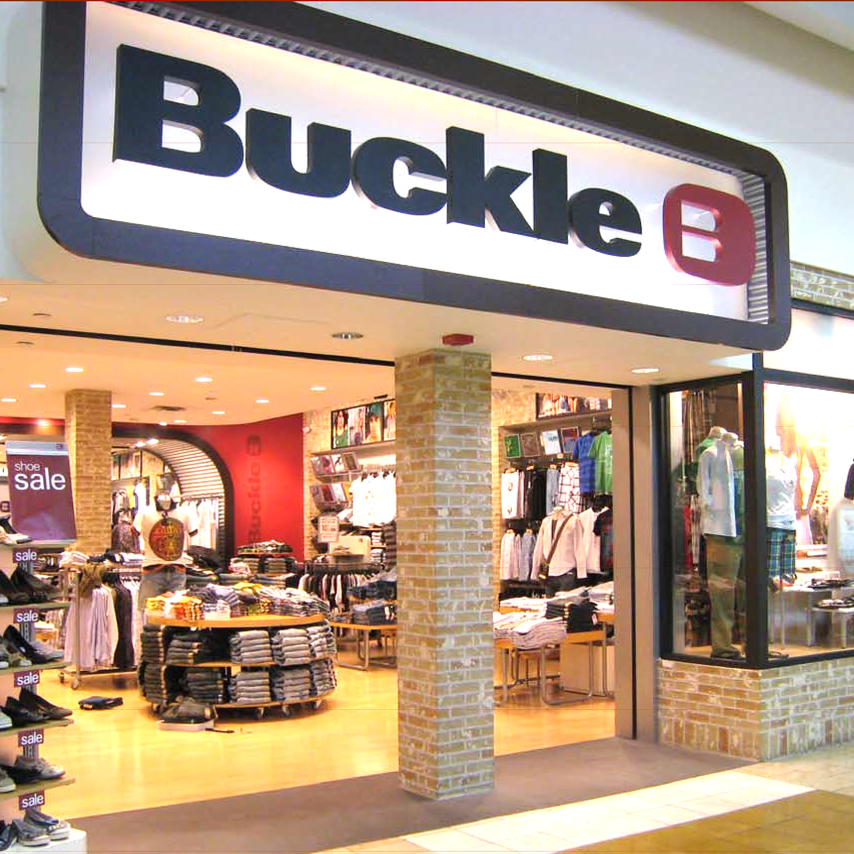 The entrance of Buckle clothing store inside a shopping mall. The store display shows men's and women's clothing, shoes, and accessories.