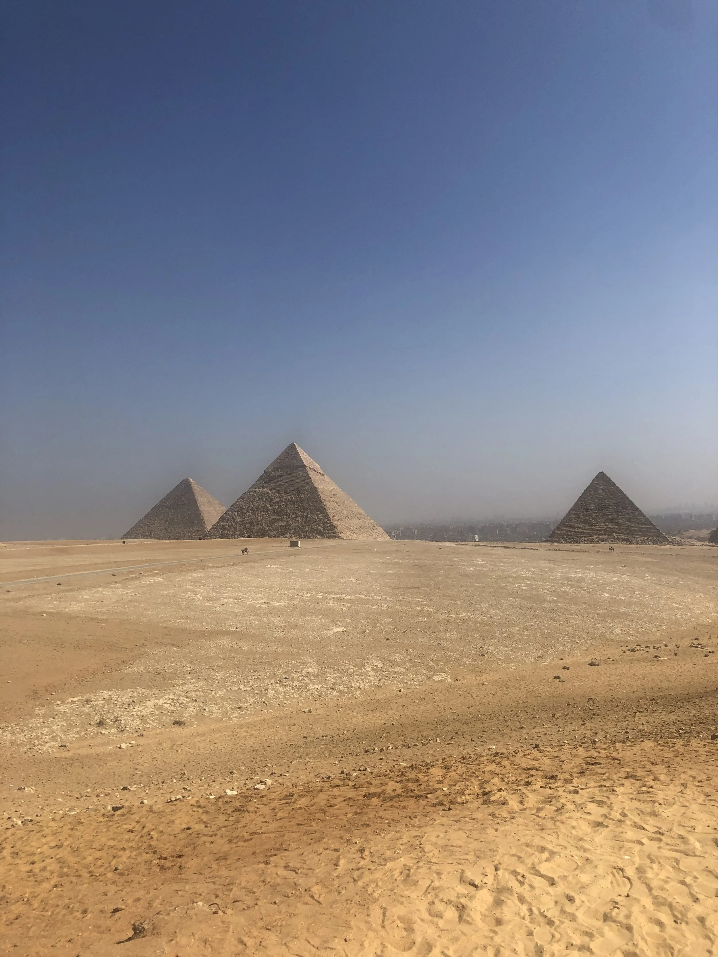 The image features three pyramids in Egypt situated in a desert landscape with a clear blue sky.