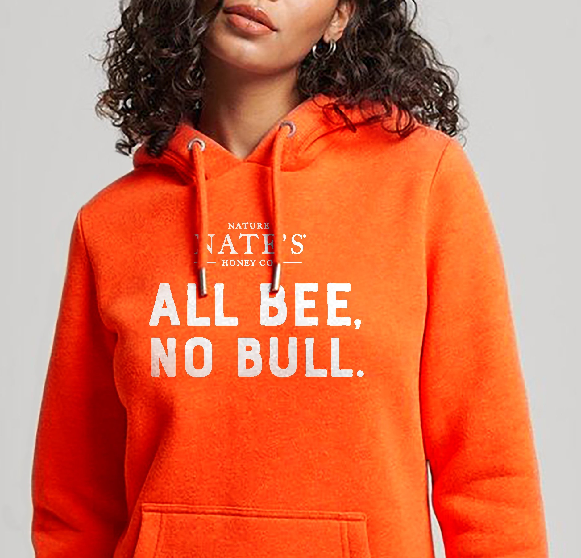 Girl wearing orange hoodie featuring the Nature Nate's Honey logo and a headline that reads, "All bee, no bull."