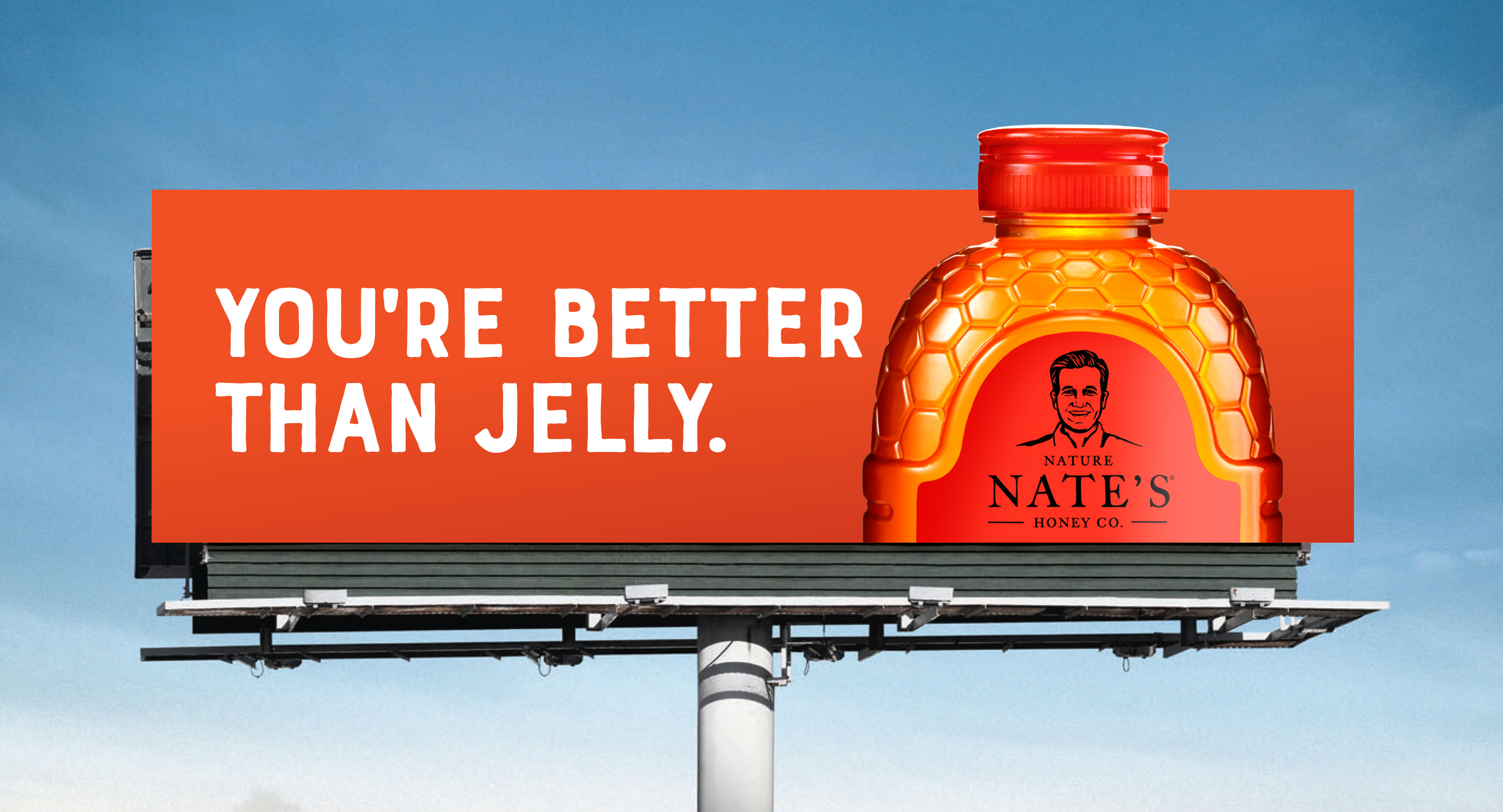 Outdoor board advertisement for Nature Nate's Honey featuring a honey bottle, bright orange background, and a headline that reads, "You're better than jelly."