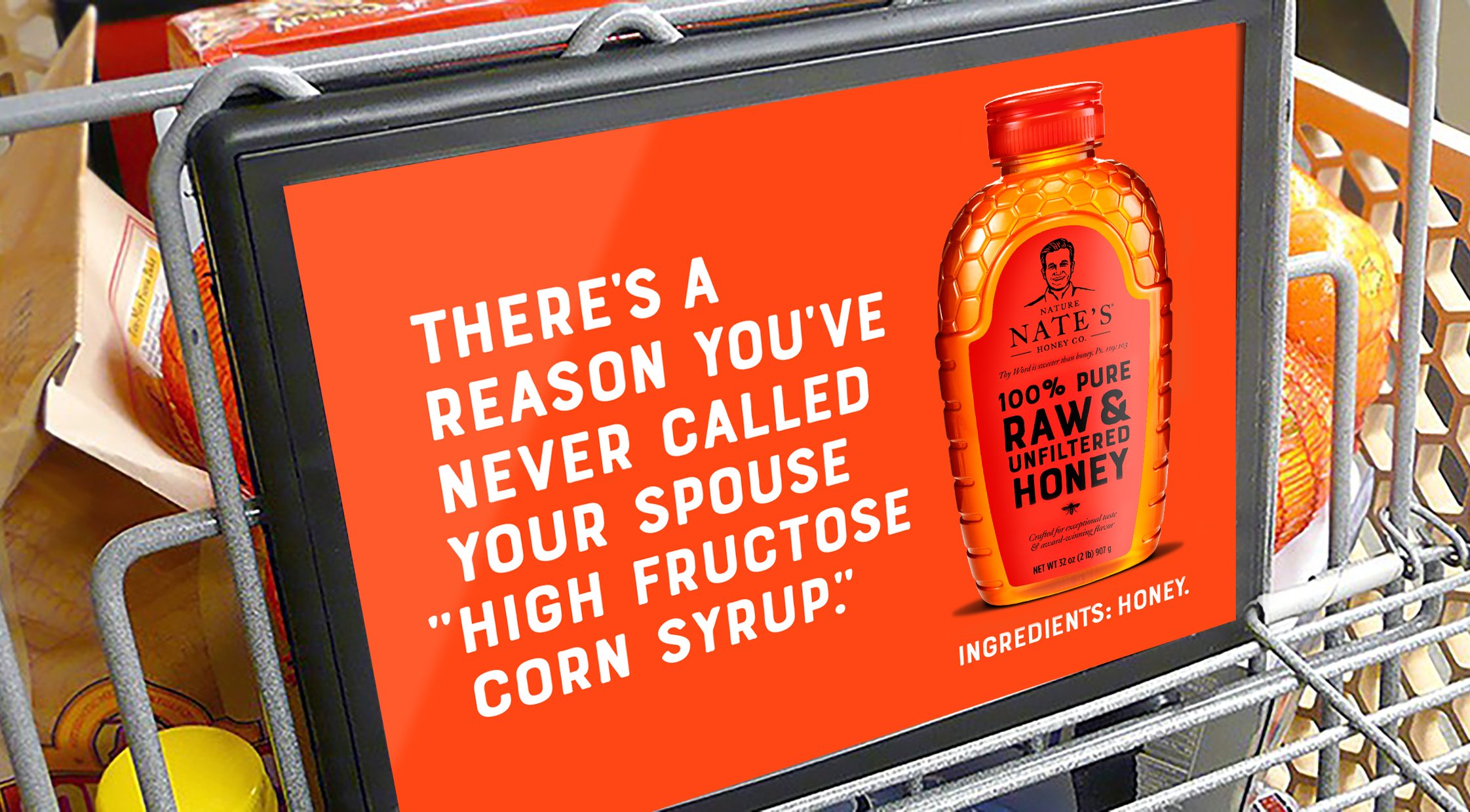 Nature Nate's Honey advertisement on a shopping cart featuring a honey bottle, bright orange background, and a headline that reads, "There's a reason you've never called your spouse "high fructose corn syrup."