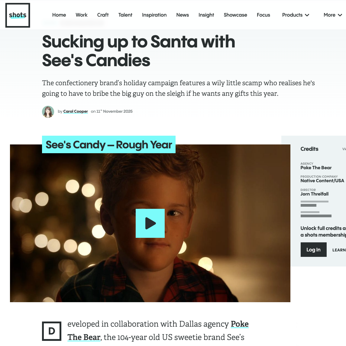 A young boy with short brown hair wearing a plaid shirt, standing in front of blurred Christmas lights, smiling at the camera.