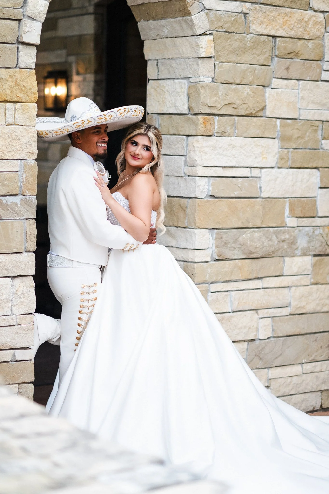 Bride and groom embracing under a stone arch at Canyonwood Ridge, photographed by Photos by Mkay.