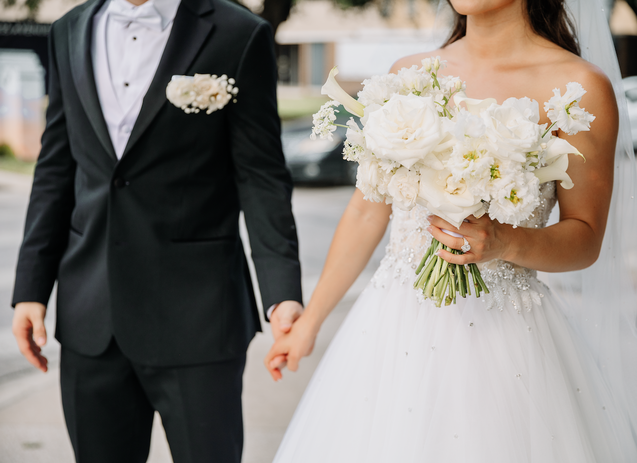 Bride and Groom Holding hands and featuring a beautiful bouquet of white flowers