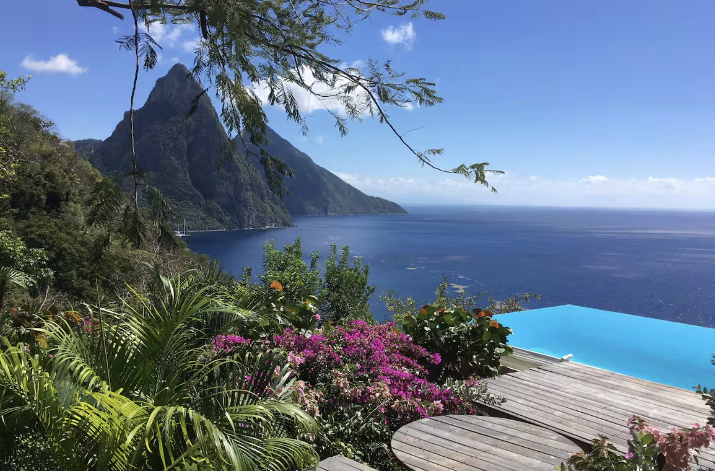 Interior of a round living room with a thatched roof, large windows, and a built-in white sectional sofa with cushions, decorated with natural wood furniture and soft lighting.