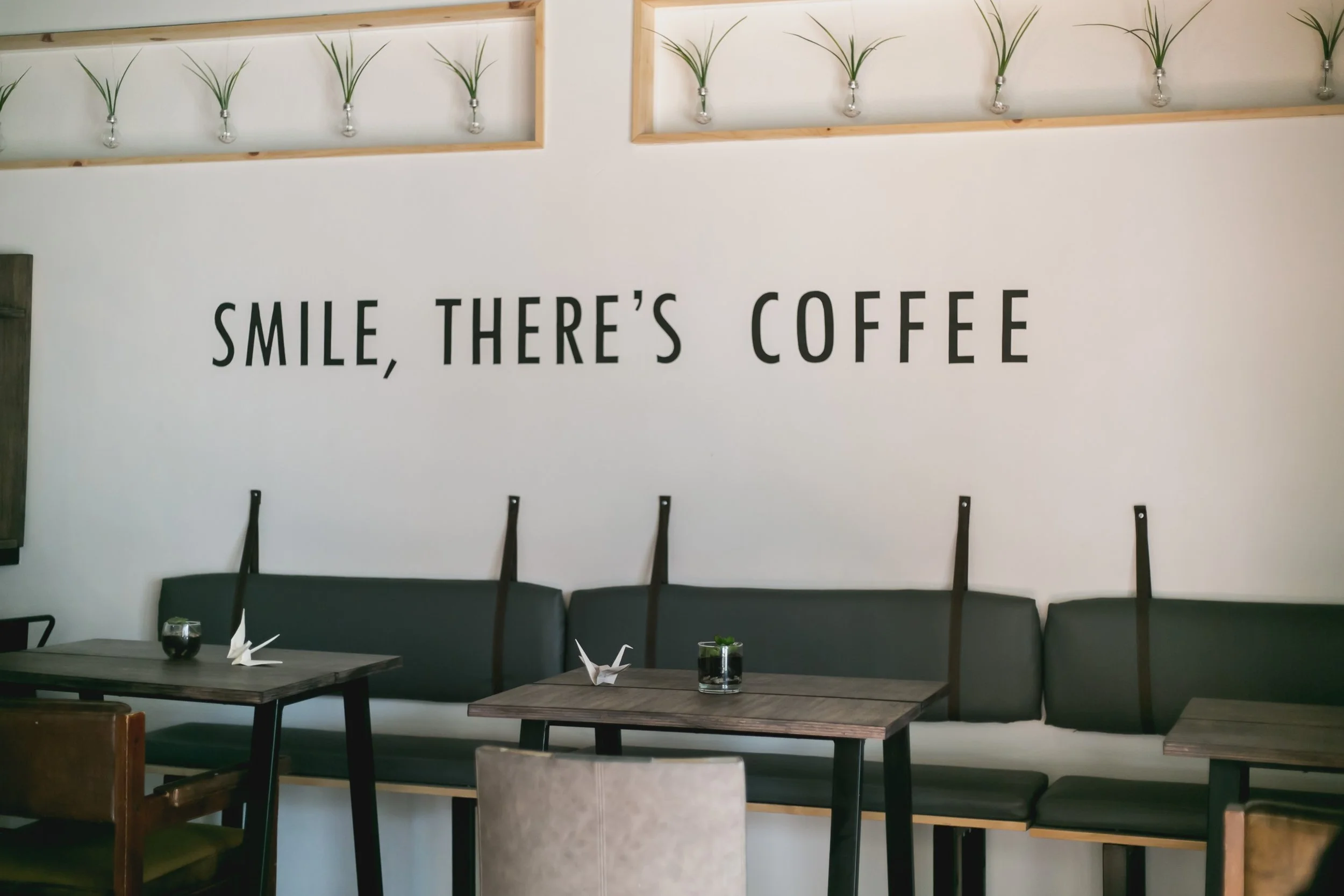 stock photo of coffee shop with wall mural that says "smile, there's coffee"