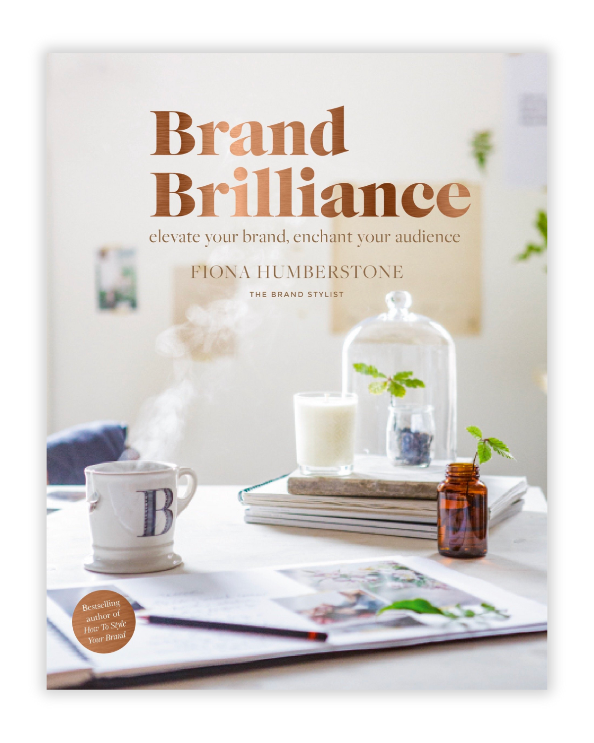 Book cover titled "Brand Brilliance" by Fiona Humberstone, featuring a minimalist aesthetic with a white background, a steaming cup, a glass jar with greenery, a small amber bottle, and some papers on a table.