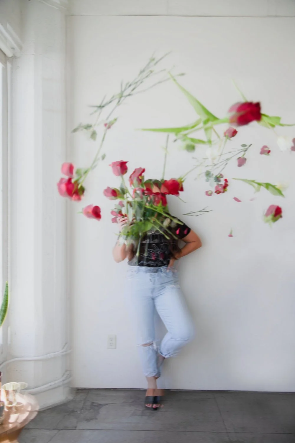creative brand portrait roses thrown at camera with woman in background