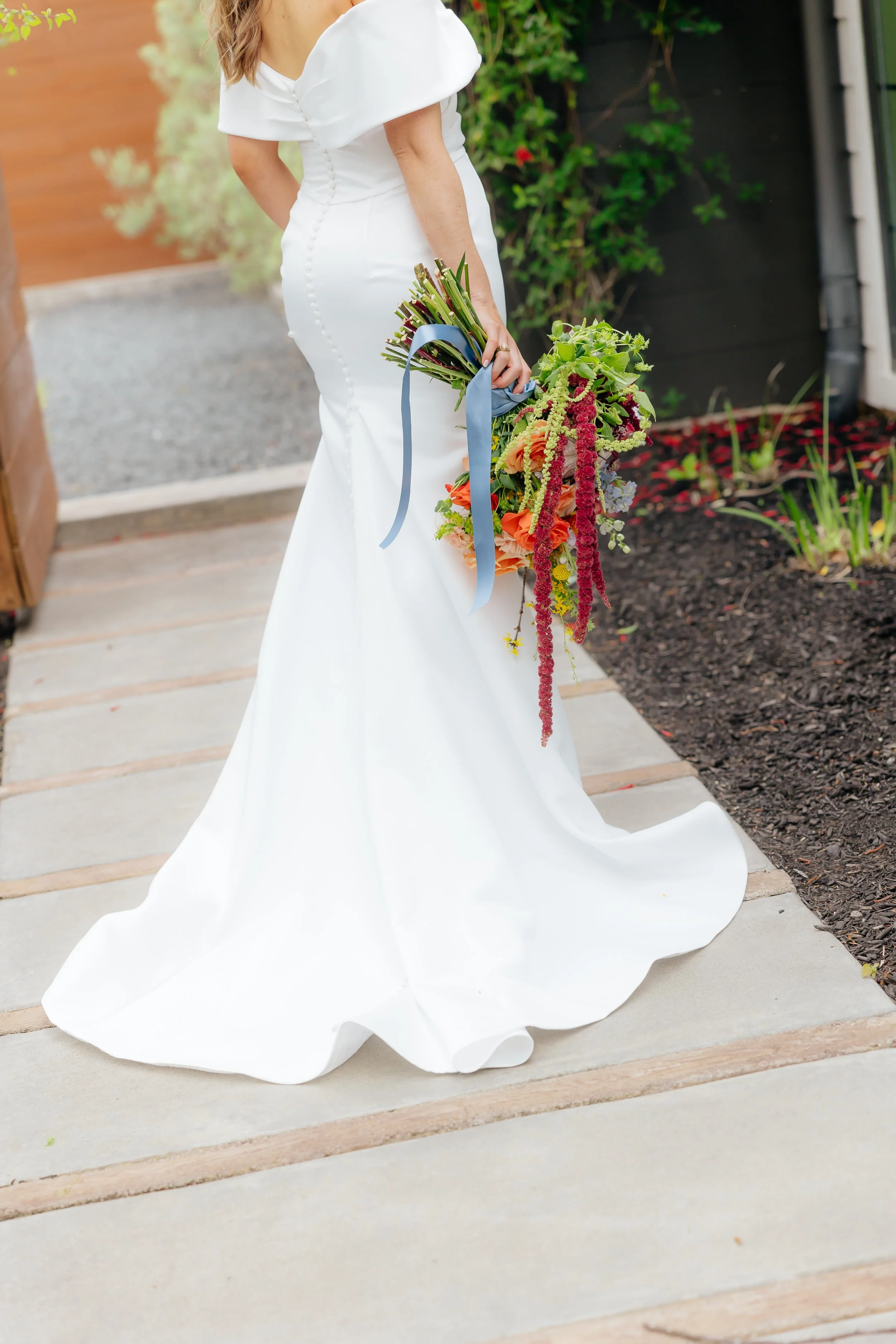 A woman wearing a white wedding dress holding a colorful bouquet of flowers.
