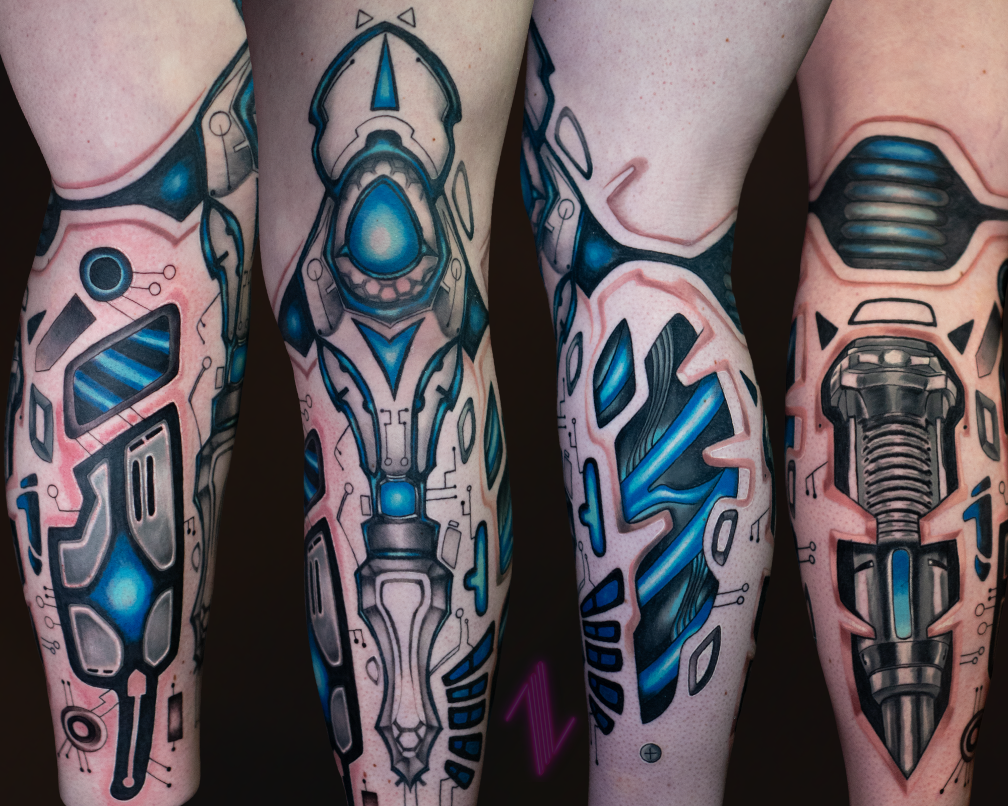 Close-up photo of four tattooed arms with futuristic, circuit-inspired designs mainly in black, blue, and gray tones.