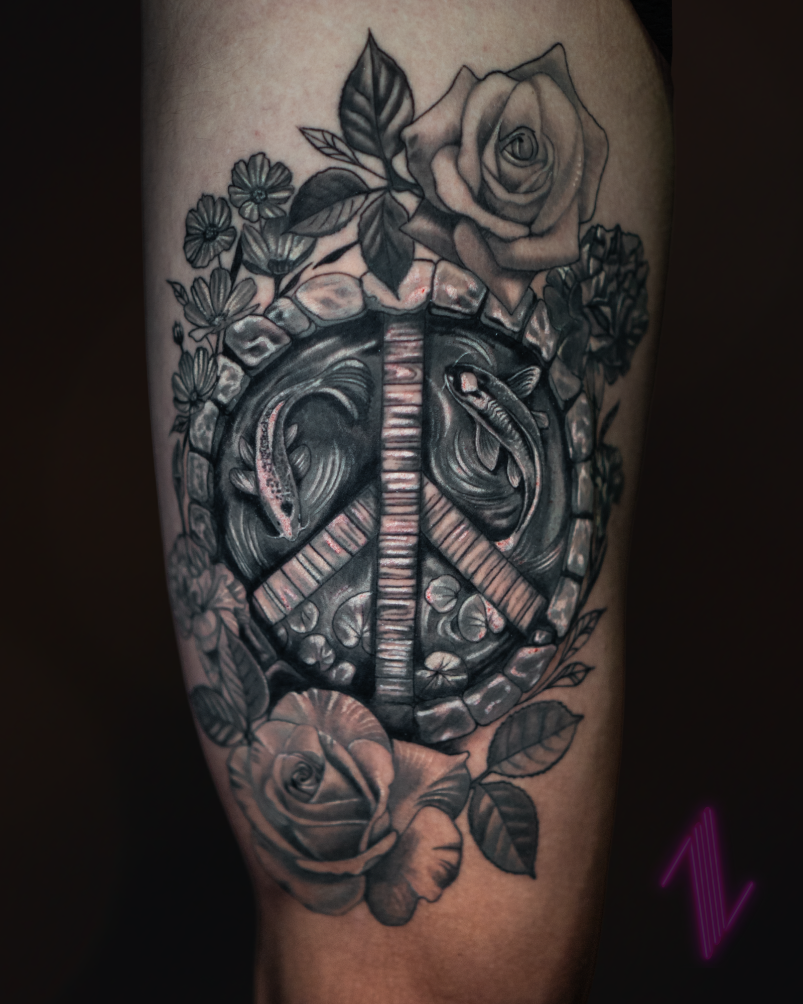 Black and gray tattoo on arm featuring a rose, smaller flowers, leaves, and a snake intertwined with a brick pattern.