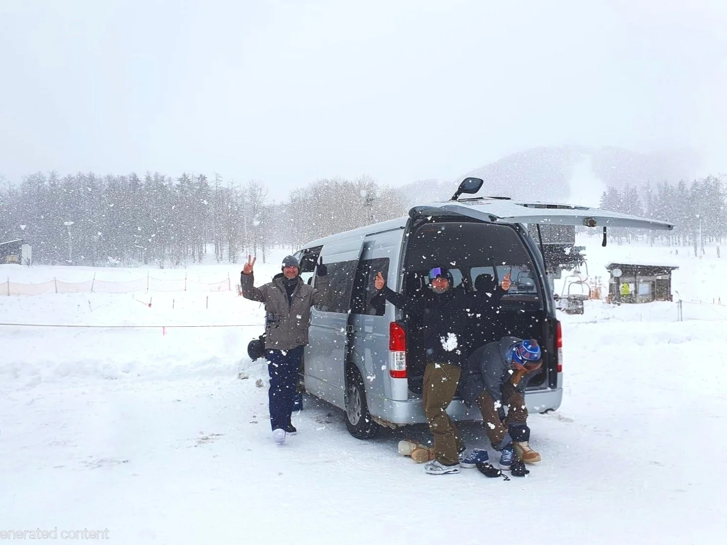 Three people in winter clothing and helmets with snowboards pose near a snow-covered van in a snowy landscape with trees and a small building in the background.