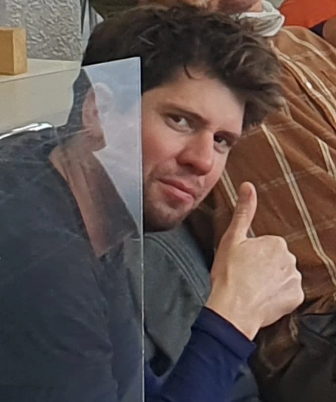 Man giving a thumbs up behind a clear partition