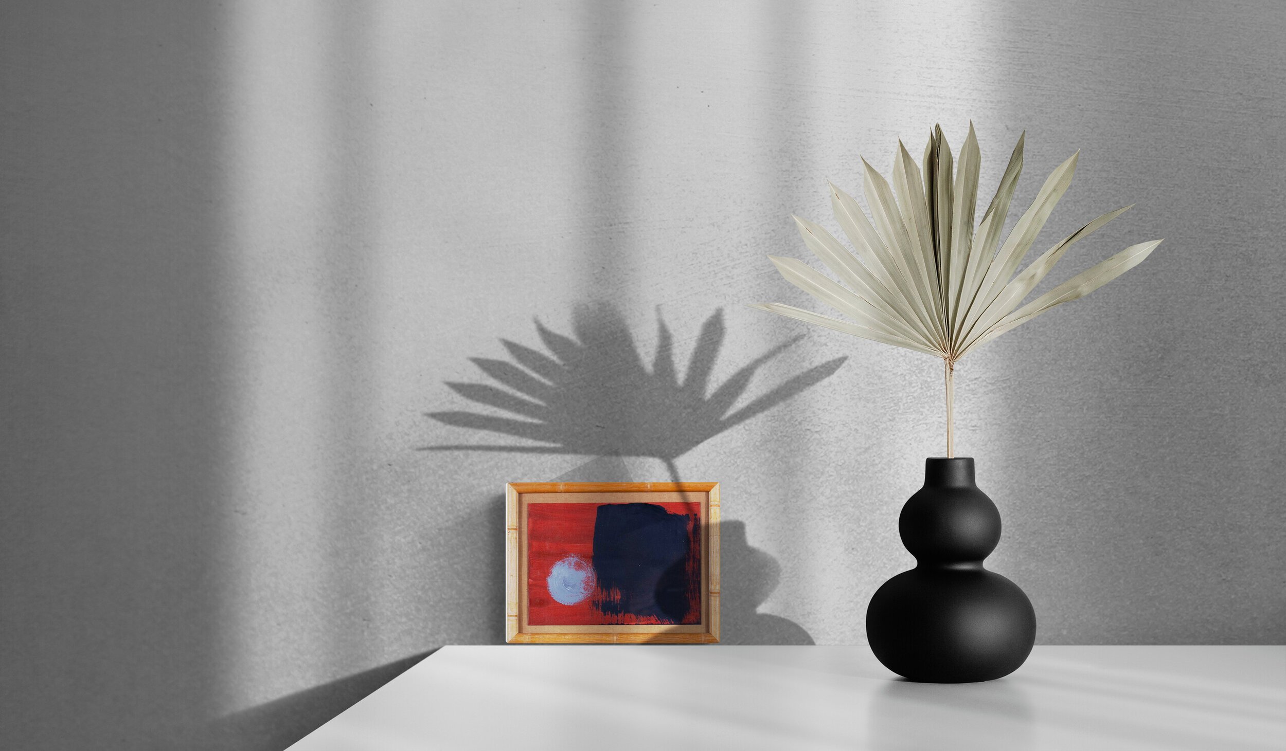 Black_vase_with_dried_leaves_on_white_table.jpg