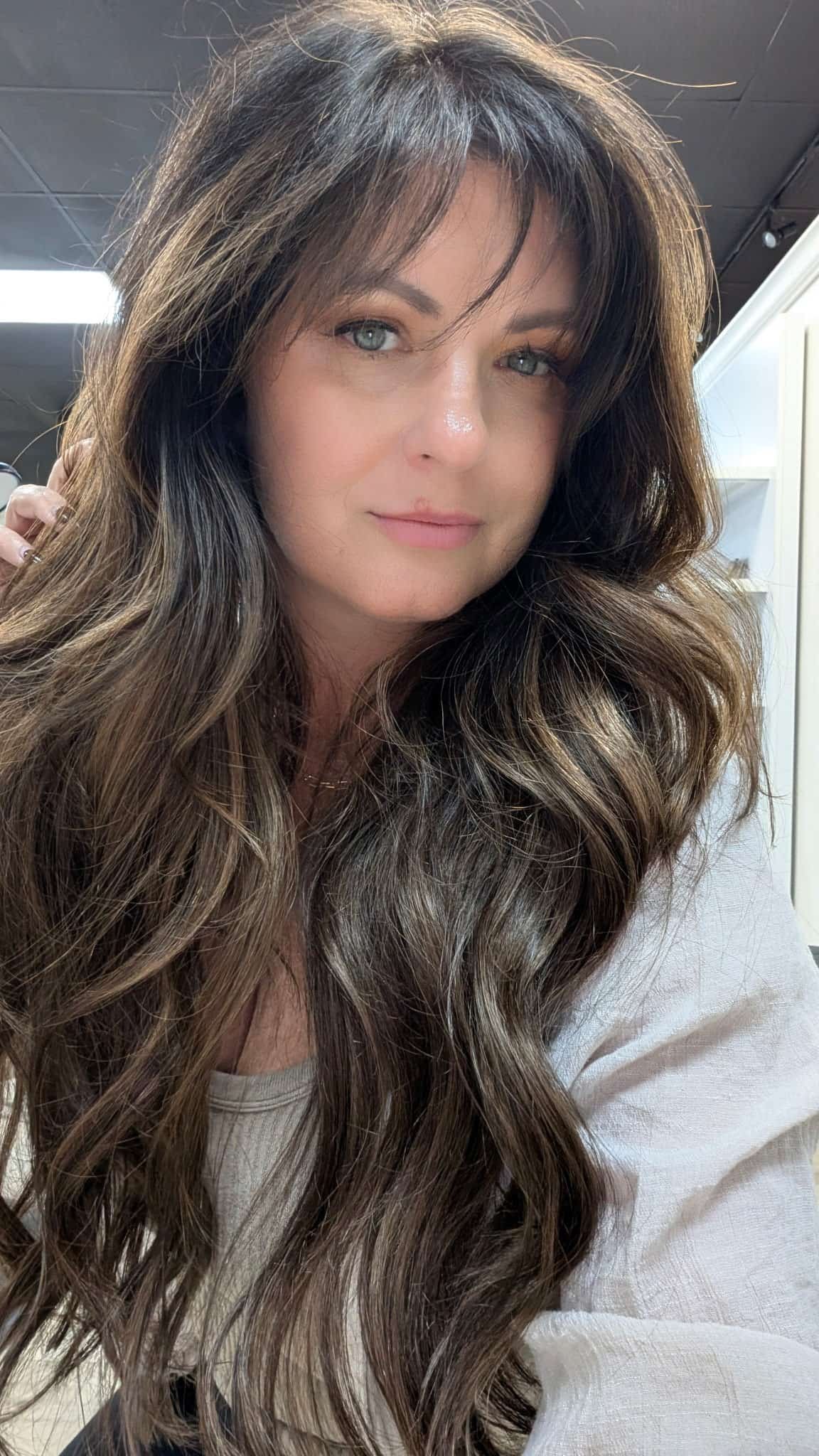 Scenic landscape with a turquoise lake, green hills, and mountains under a cloudy sky.