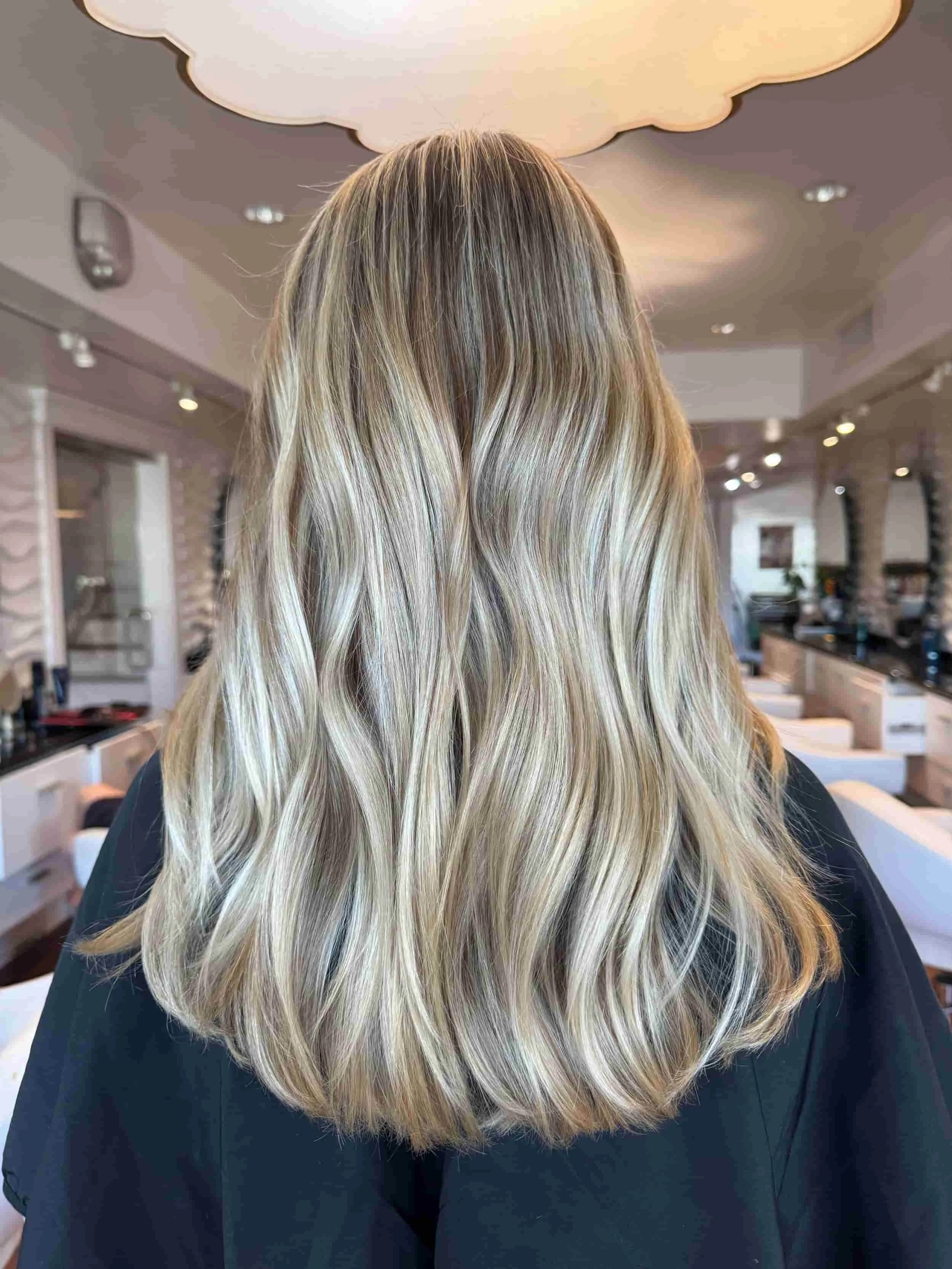 Back view of a person with long, wavy blonde hair in a salon Private hair studio Tampa.