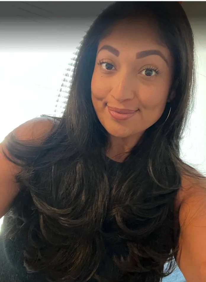 A landscape of rolling green hills leading to a modern building, with snow-capped mountains in the background and a cloudy sky above.