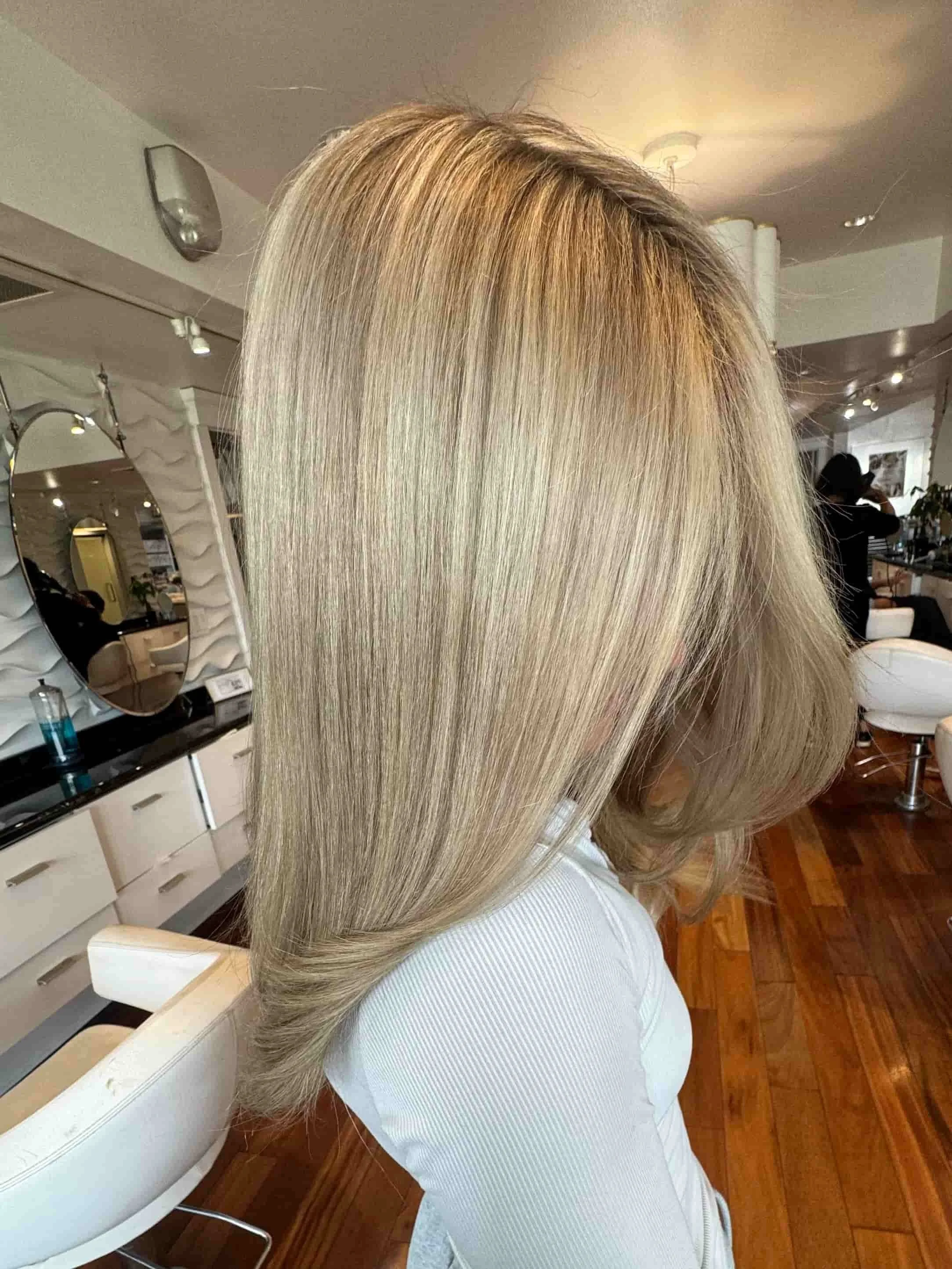 Woman with long, straight, blonde hair sitting in a salon chair.