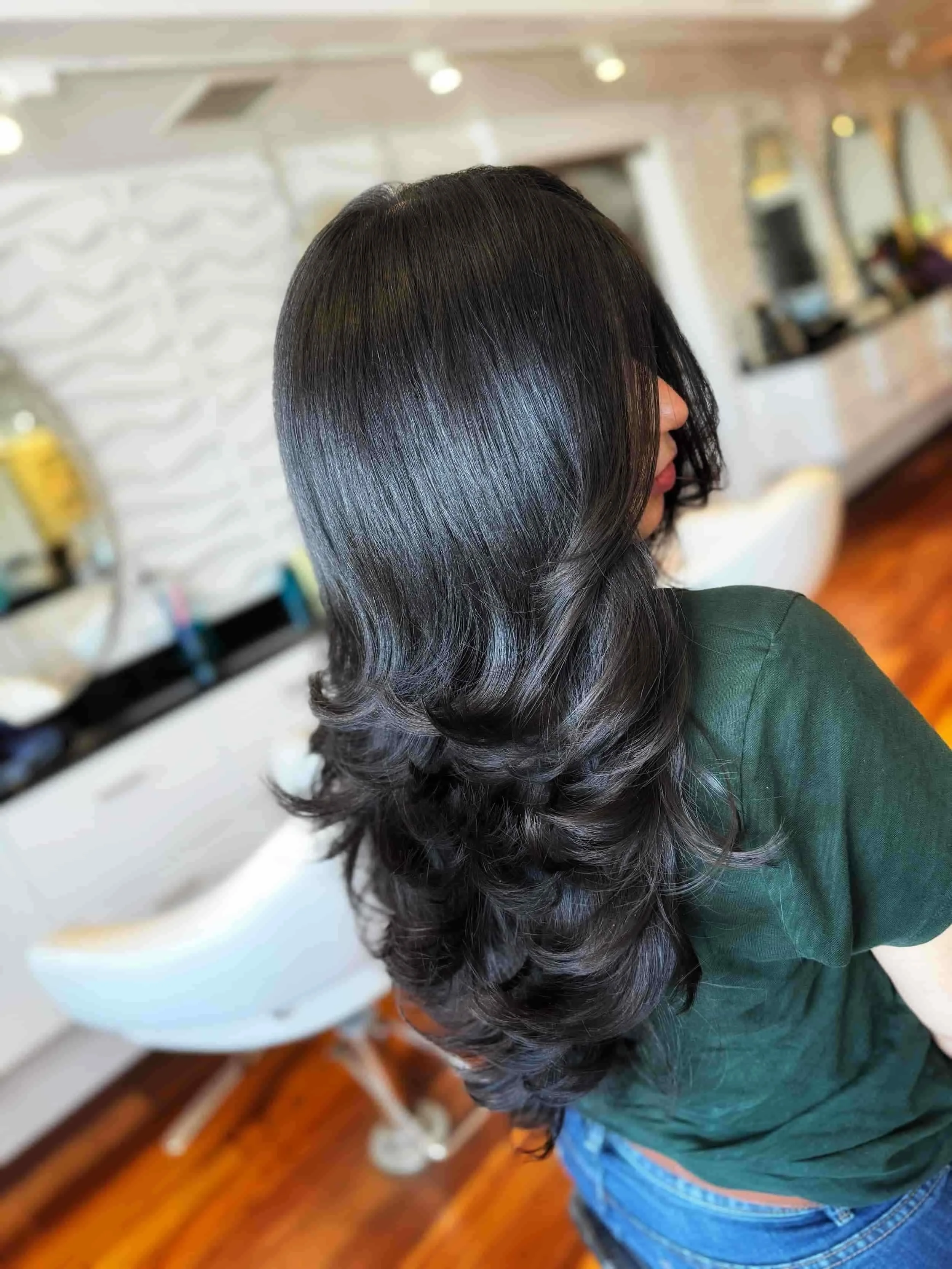 Woman with long, dark, wavy hair in a hair salon.
