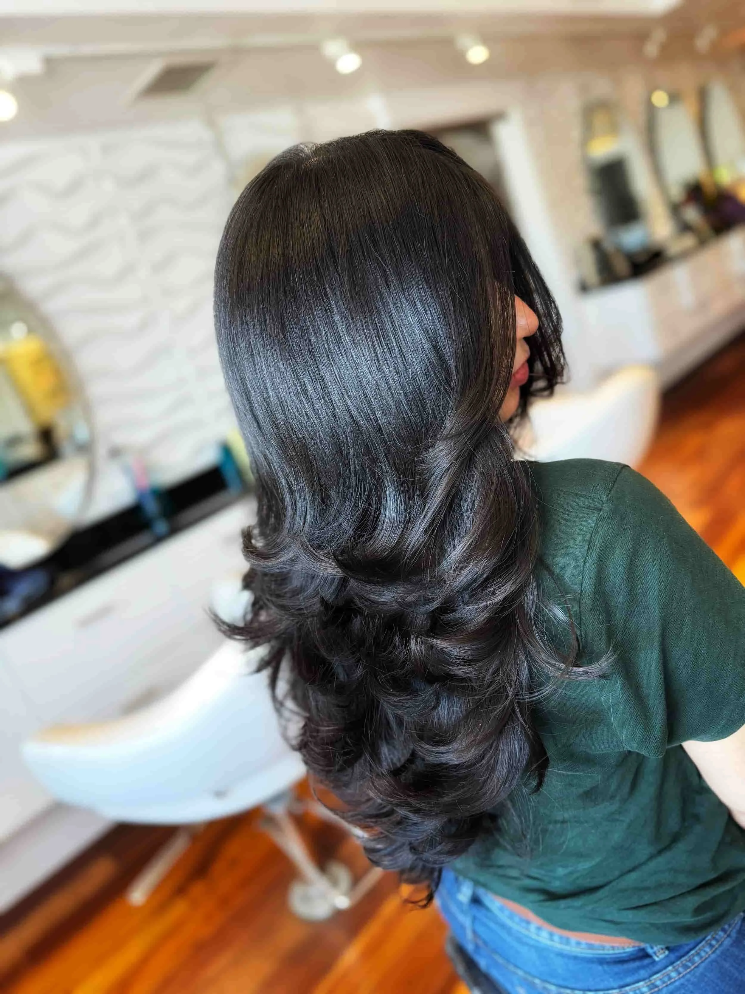 Woman with long, dark, wavy hair in a hair salon.