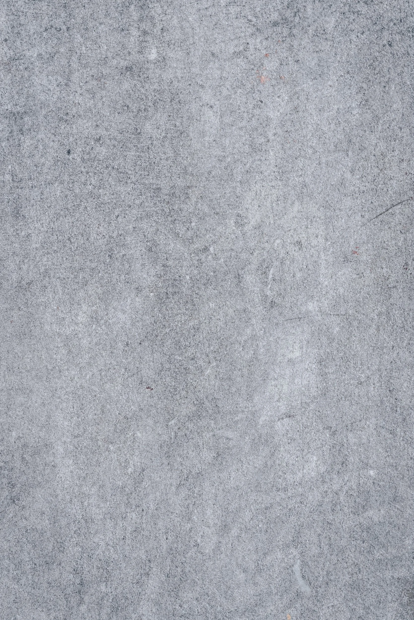 Gray concrete surface with a few small reddish spots.