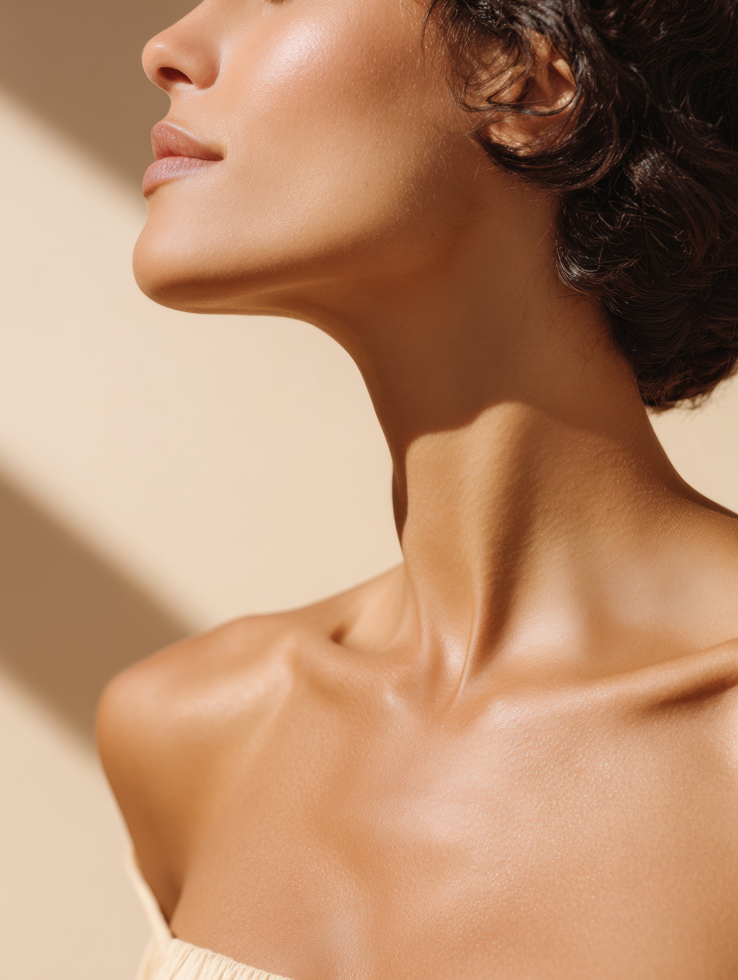 Close-up of a woman's face, neck, and shoulder, with smooth, glowing skin, set against a beige background.