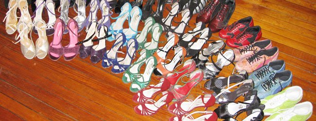 A collection of colorful women's high-heeled shoes arranged on a wooden floor.