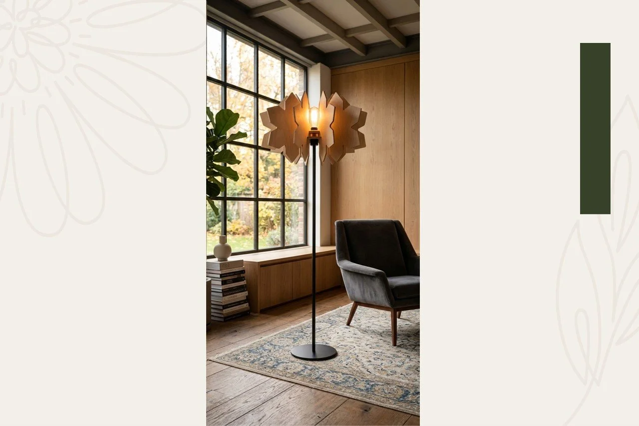 A modern living room corner featuring a black armchair, a tall floor lamp with a decorative wooden shade and bulb, a large window with a view of trees, a potted plant, and a stack of books on a wooden bench.