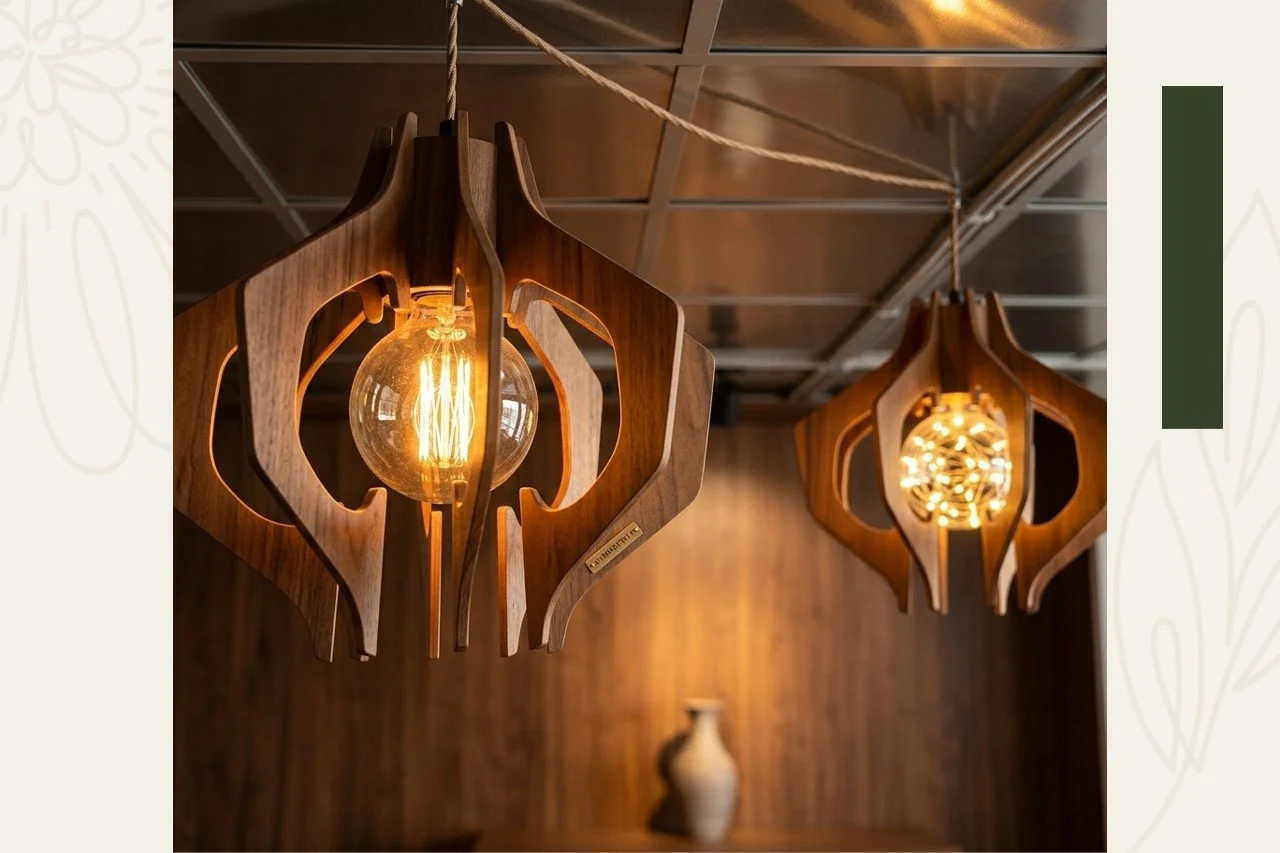 Two wooden pendant light fixtures with exposed filament bulbs hanging from a ceiling in a room with wood-paneled walls and a ceramic vase on a table.