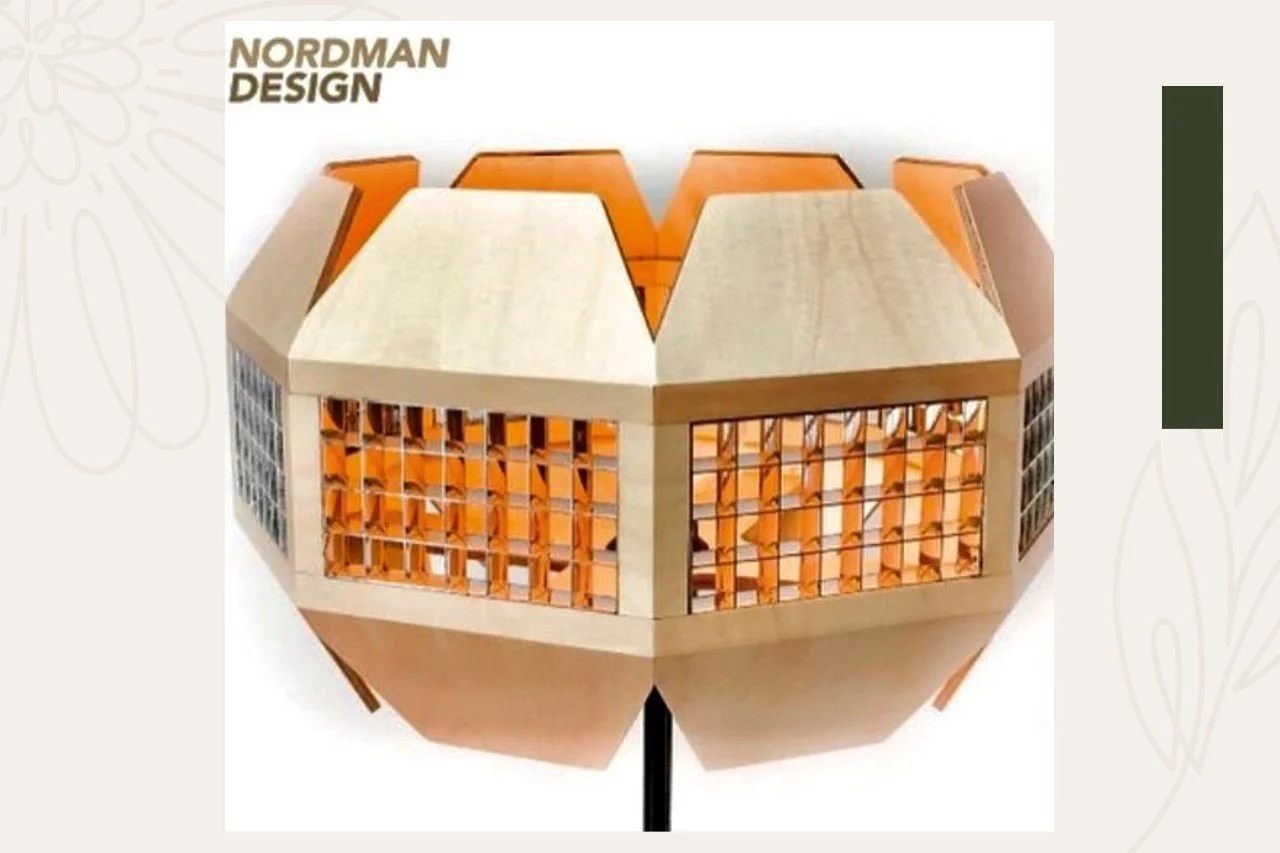 A geometric wooden model building with a hexagonal shape, featuring large windows and a sloped roof, labeled 'Nordman Design'.