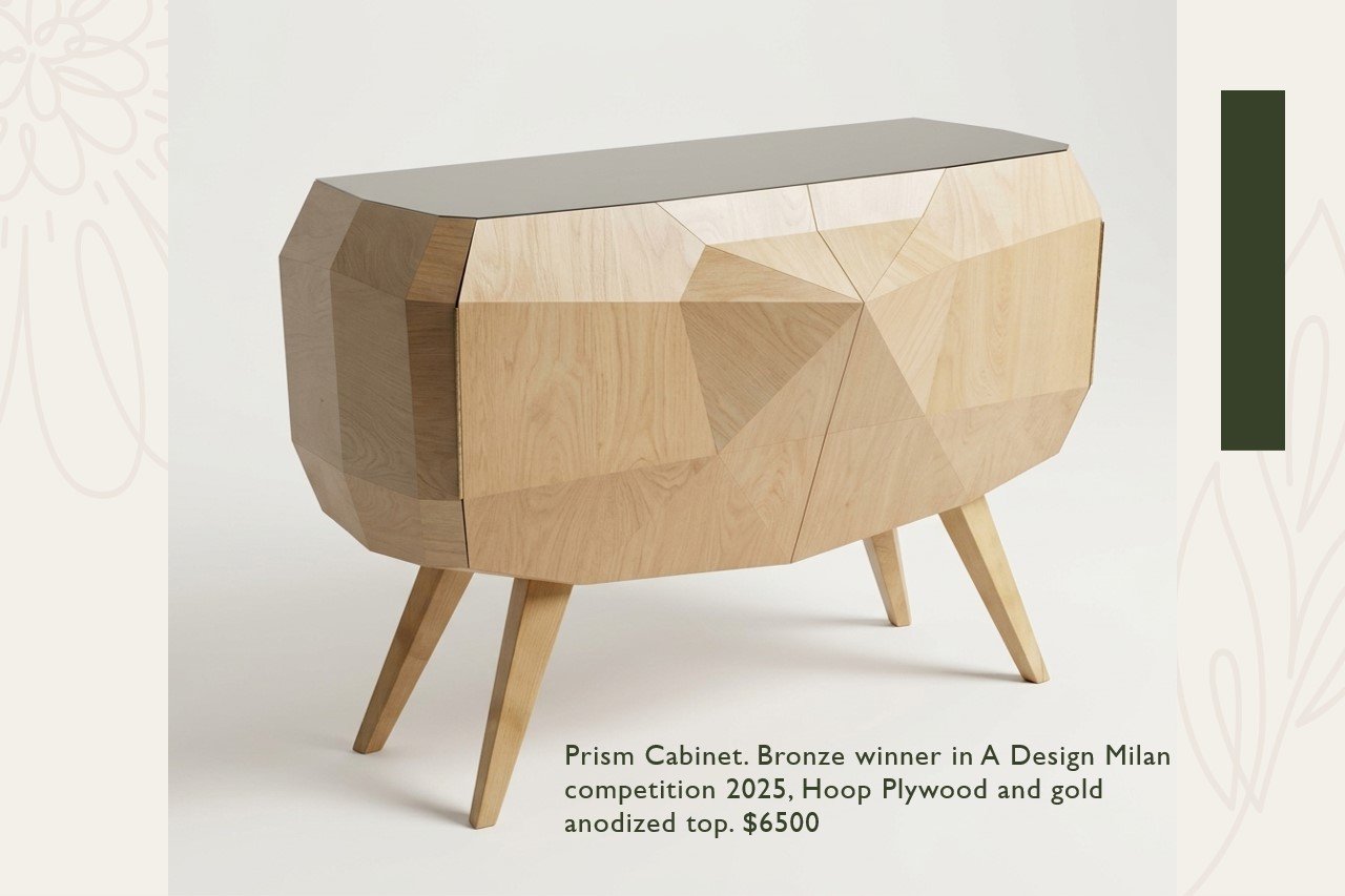 A modern prism-shaped cabinet with a bronze winner badge, made of hoop plywood with a gold anodized top, on angled wooden legs.