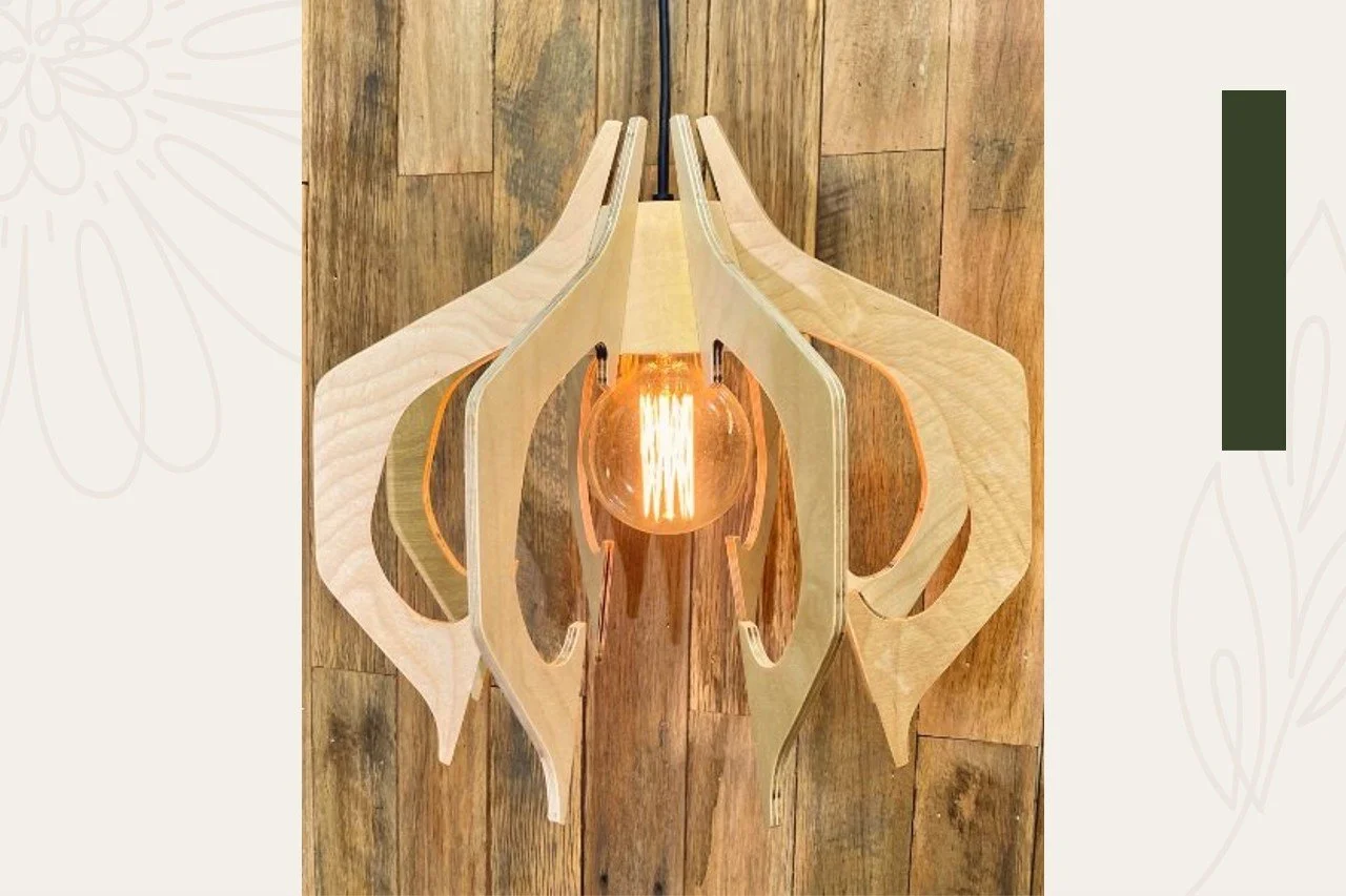 Modern pendant light fixture with a wooden and glass design, illuminated with a warm Edison-style bulb, hanging over a wooden surface.