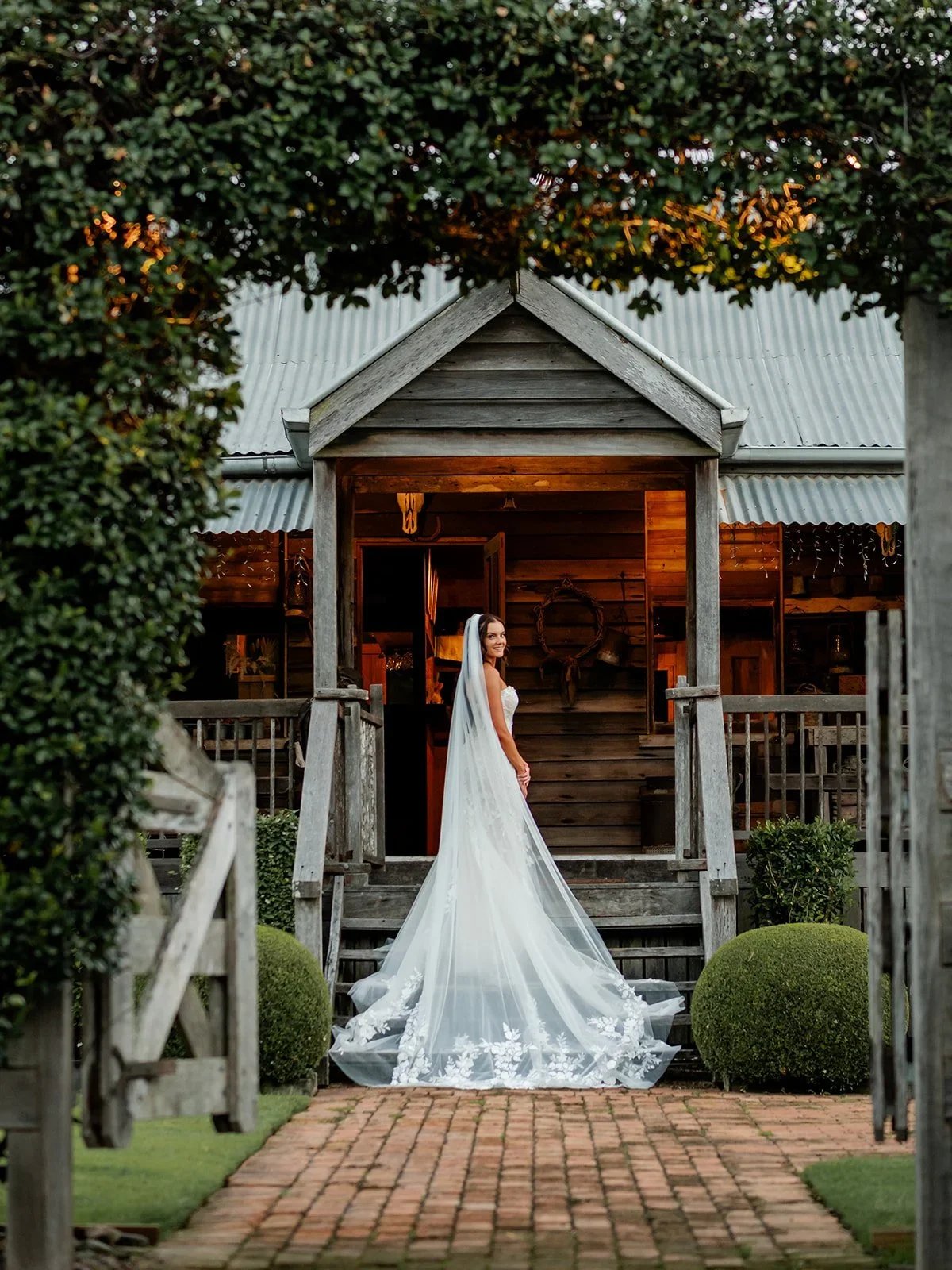 Chloe standing at the entrance of the reception building with her veil flowing — Sean Reefman Photography