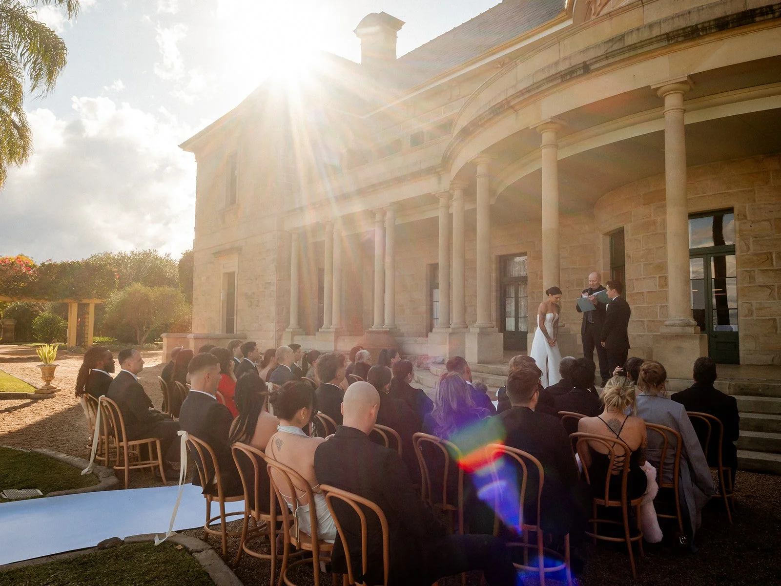 Wide outdoor wedding ceremony at Jimbour House with dramatic sunflare — Darling Downs wedding by Sean Reefman Photography