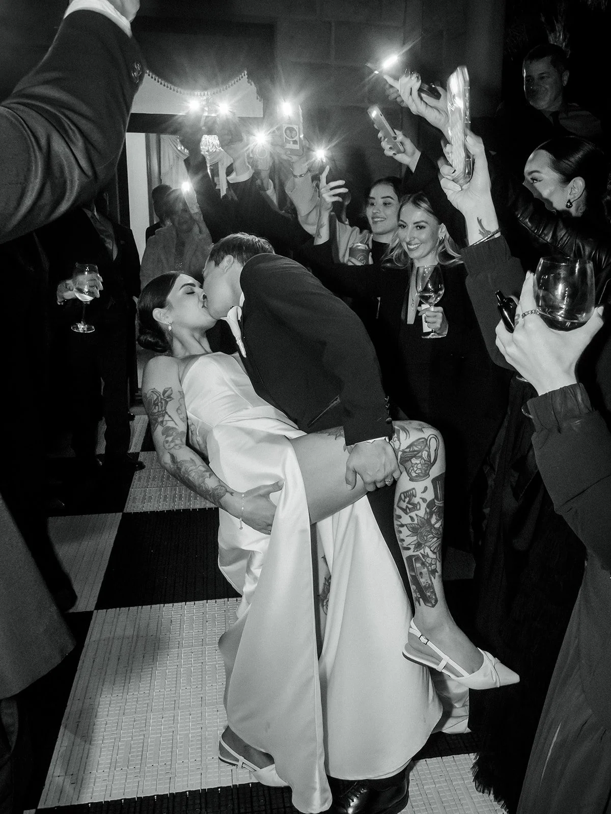 First dance dip kiss in black and white surrounded by guests holding phone lights — Jimbour House wedding by Sean Reefman Photography