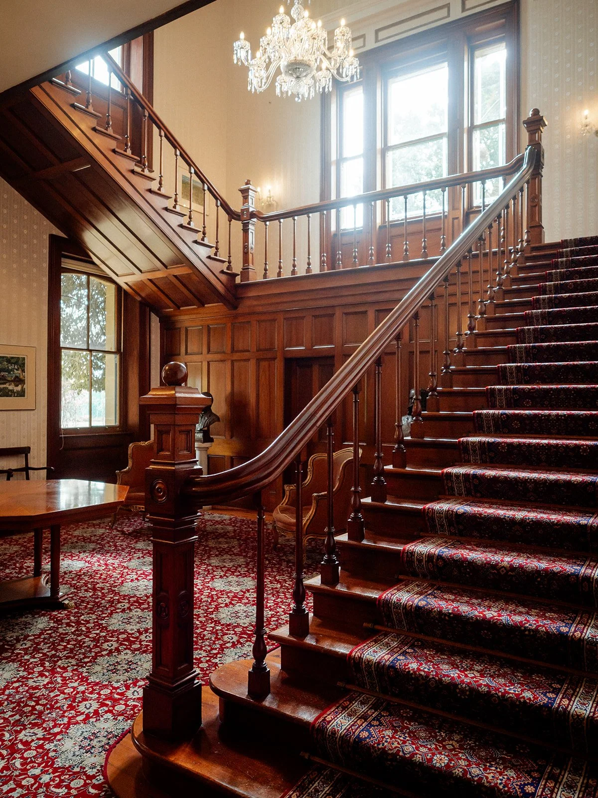Grand wooden staircase inside Jimbour House with crystal chandelier — Darling Downs wedding venue interior