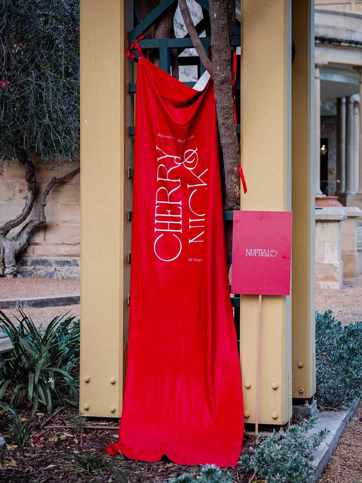 Red welcome banner reading Cherry and Nick at the entrance to Jimbour House wedding venue — Sean Reefman Photography