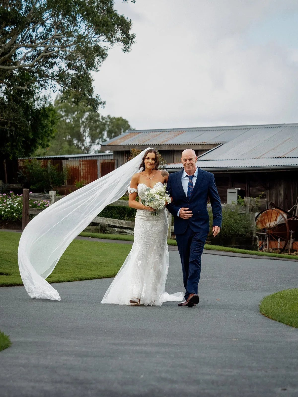 Chloe and James walking hand in hand with her veil flowing behind them — Sean Reefman Photography