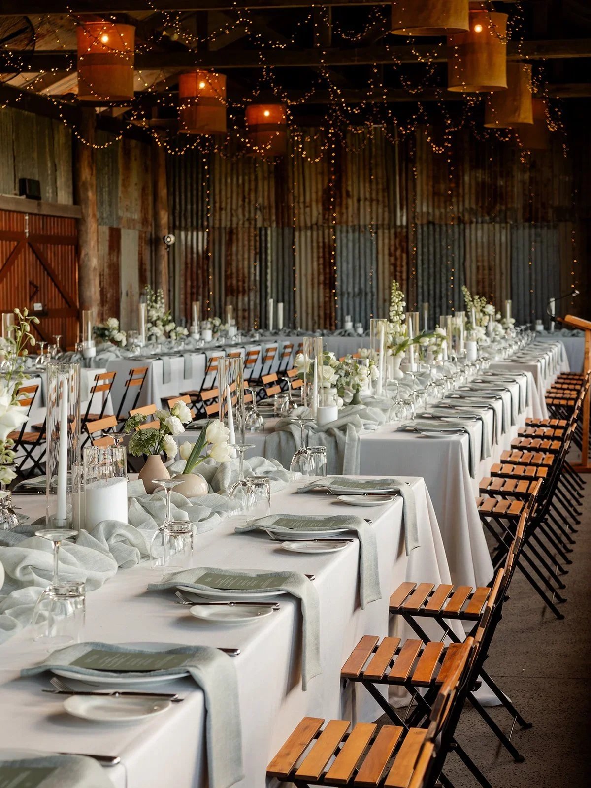 Long banquet tables set up inside the Yandina Station reception barn with fairy lights overhead — Sean Reefman Photography