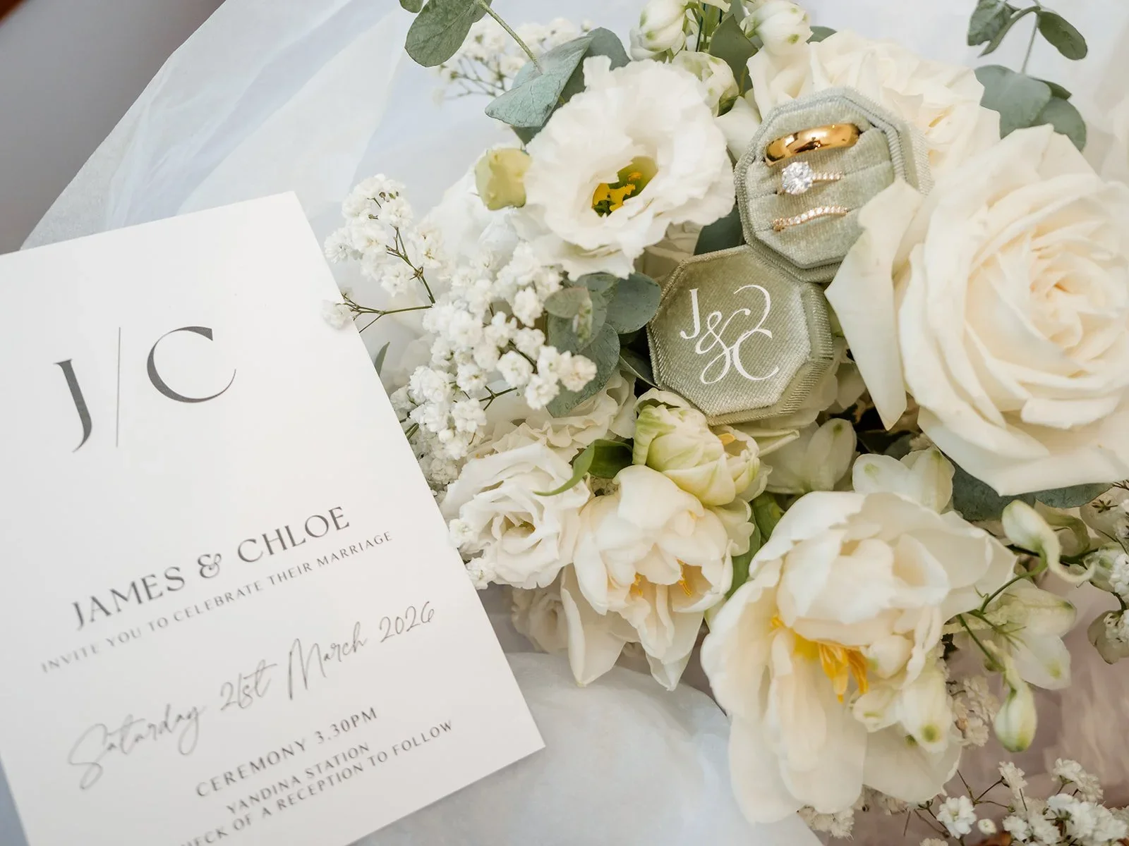 Wedding invitation and rings styled with white florals in a flat lay detail shot — Sean Reefman Photography