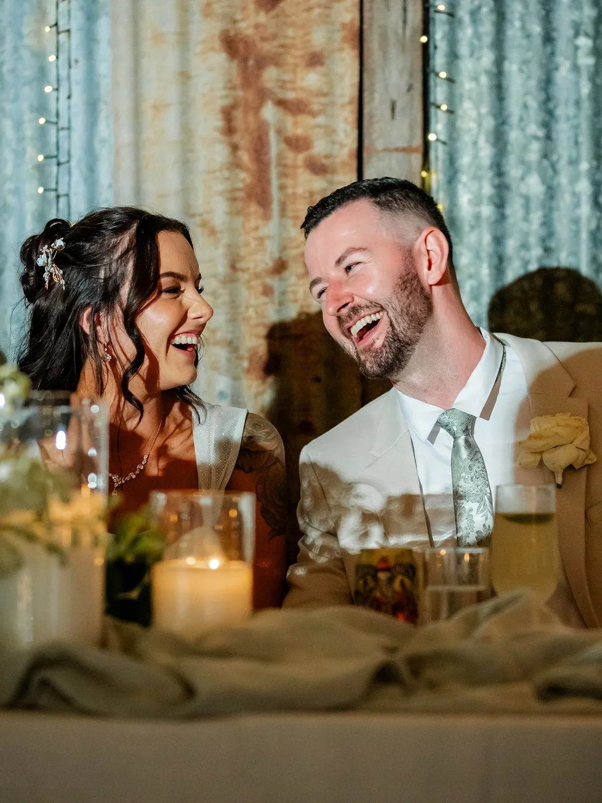 Chloe and James laughing together at their reception table — Sean Reefman Photography