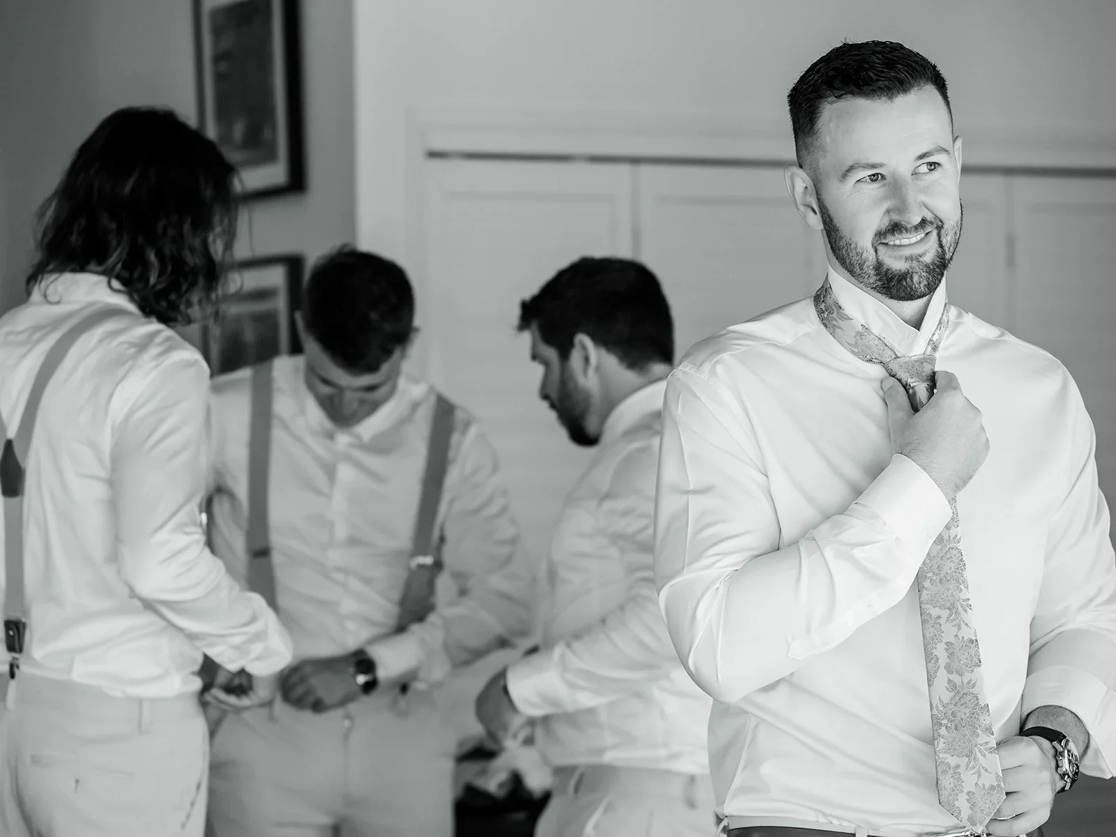 Groomsmen helping each other get ready before the ceremony in black and white — Sean Reefman Photography