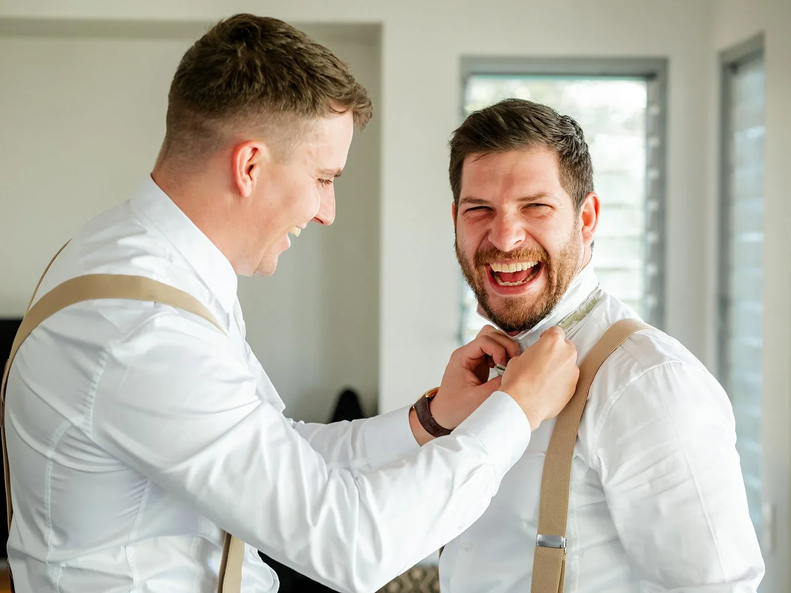James laughing while getting ready in his suspenders on the wedding morning — Sean Reefman Photography